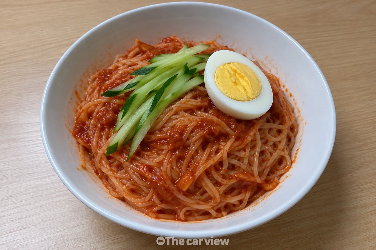 흰 그릇에 담은 비빔국수 위로 붉은 사과 양념이 고르게 버무려진 모습. / 기사 이해를 돕기 위한 생성형 이미지