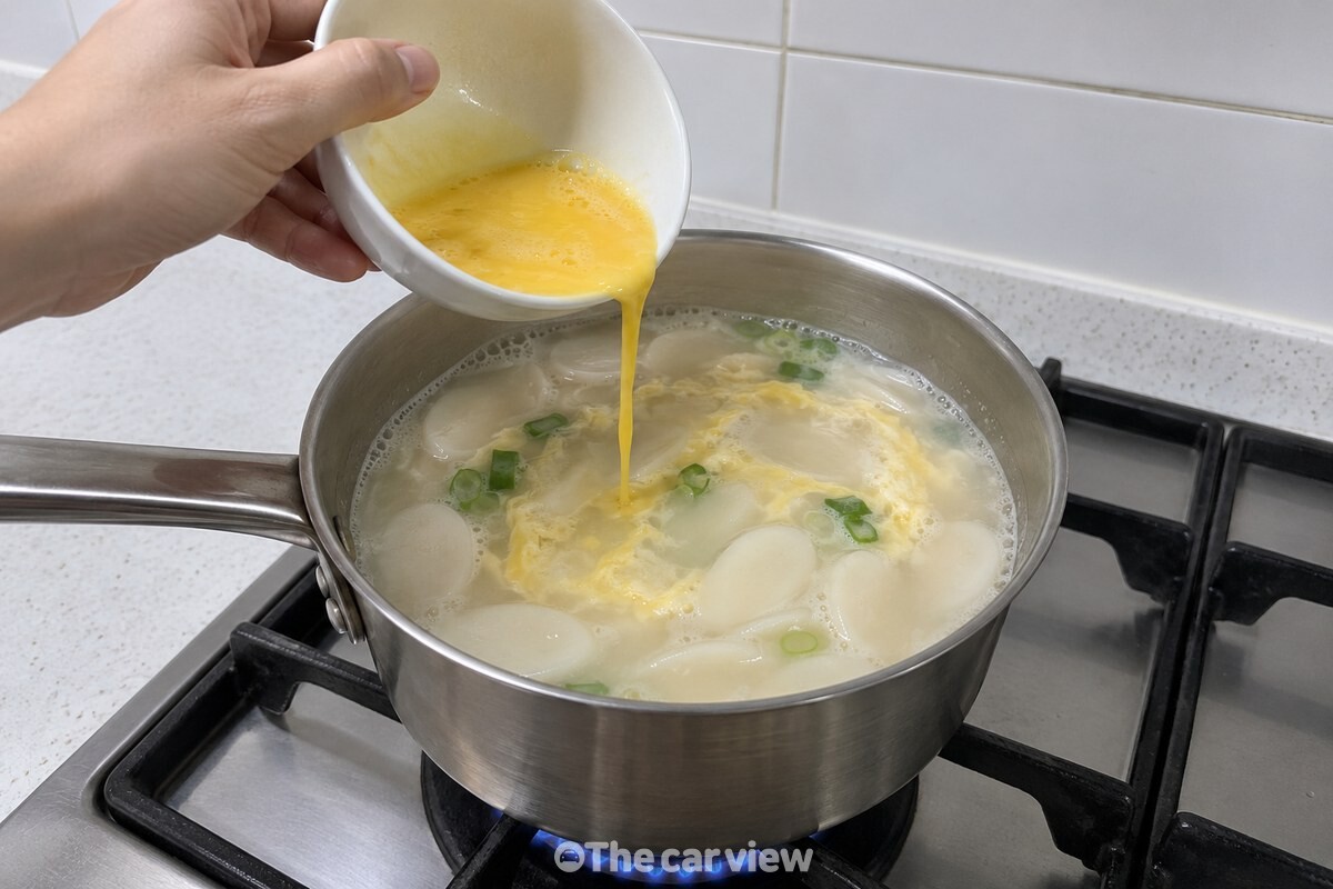 조랭이떡 국물 위로 곱게 푼 달걀을 둘러 붓는 조리 단계. / 기사 이해를 돕기 위한 생성형 이미지