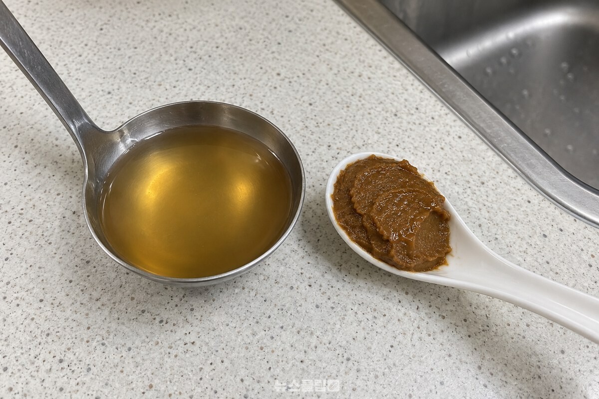 맑은 멸치 육수를 담은 작은 국자와 된장 한 숟가락을 나란히 둔 조리대. / 기사 이해를 돕기 위한 생성형 이미지