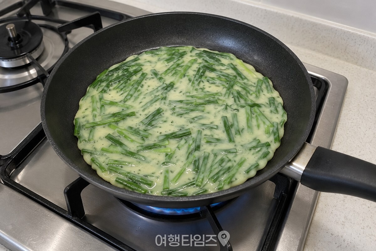 얇게 썬 부추가 반죽에 고르게 섞여 팬 위에 펼쳐져 있다. / 기사 이해를 돕기 위한 생성형 이미지