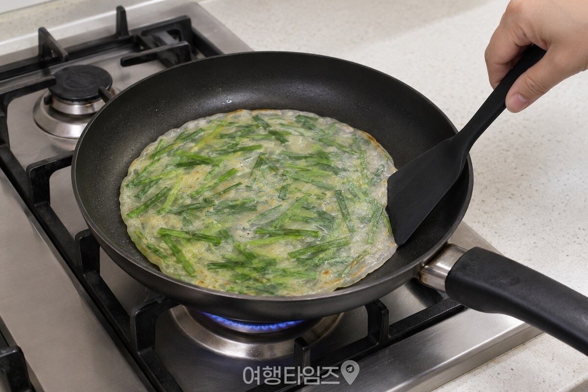 뒤집개가 라이스페이퍼 가장자리를 부추전 반죽에 가볍게 눌러 붙이고 있다. / 기사 이해를 돕기 위한 생성형 이미지