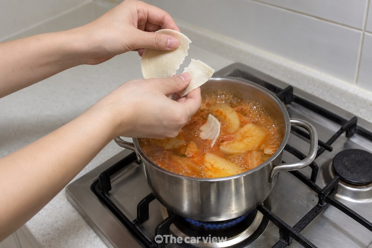 깨끗한 손으로 찢은 만두피 조각을 끓는 국물 위에 떨어뜨리고 있다. / 기사 이해를 돕기 위한 생성형 이미지