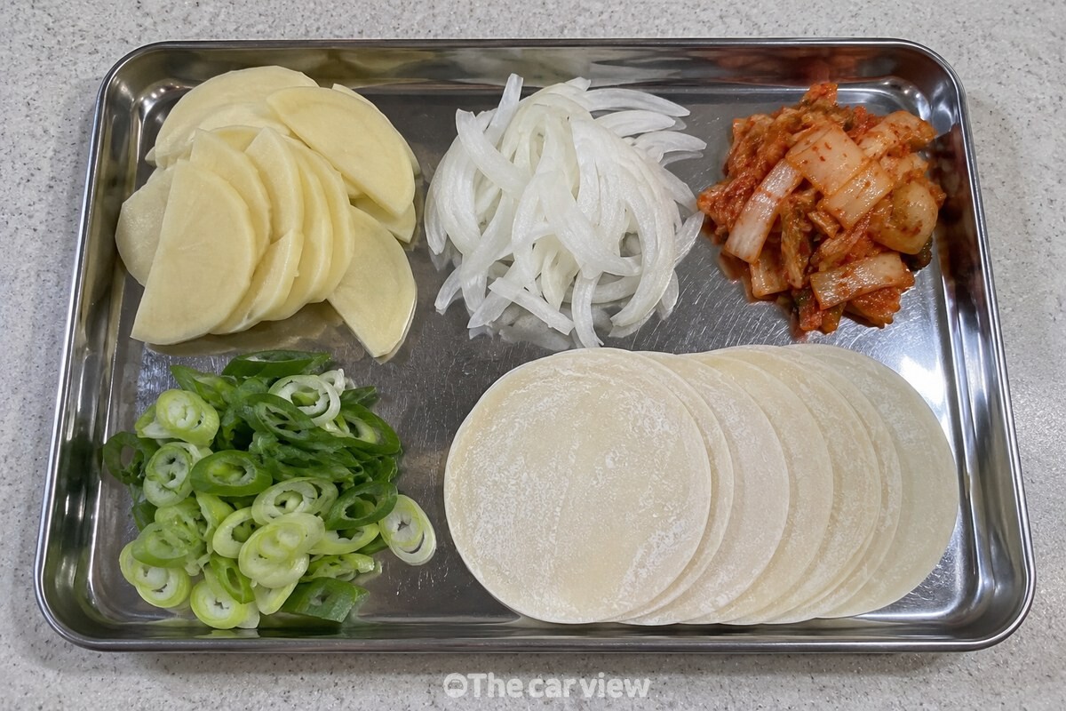 얇게 썬 감자와 양파, 한입 크기 김치, 만두피를 조리 전 준비한 모습이다. / 기사 이해를 돕기 위한 생성형 이미지