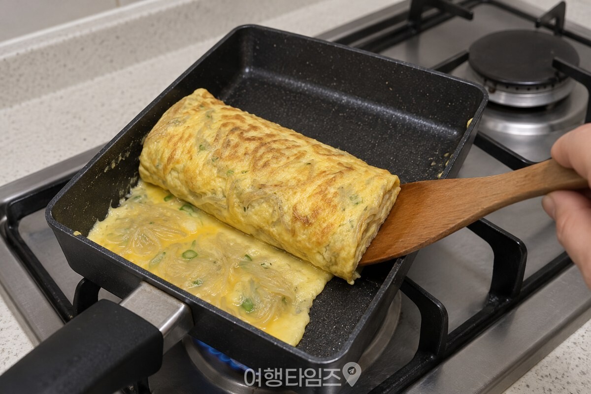 사각 팬 한쪽에서 두툼하게 말린 당면 계란말이를 뒤집개로 굴리고 있다. / 기사 이해를 돕기 위한 생성형 이미지