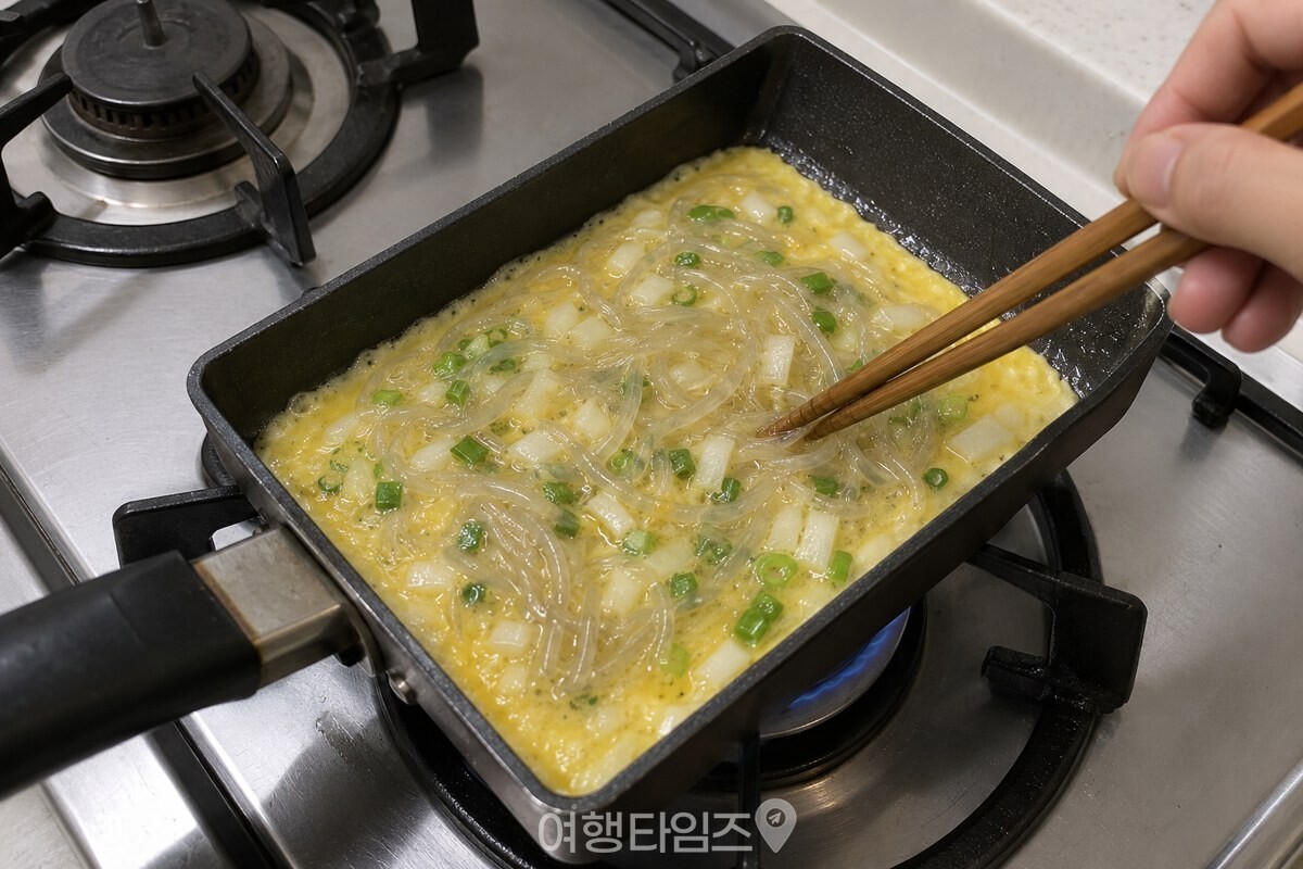 약한 불의 팬에서 당면이 든 달걀물을 젓가락으로 고르게 펴고 있다. / 기사 이해를 돕기 위한 생성형 이미지