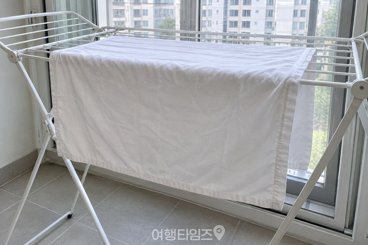 흰 면 베개커버를 접이식 건조대 위에 넓게 펴 말리는 장면. / 기사 이해를 돕기 위한 생성형 이미지