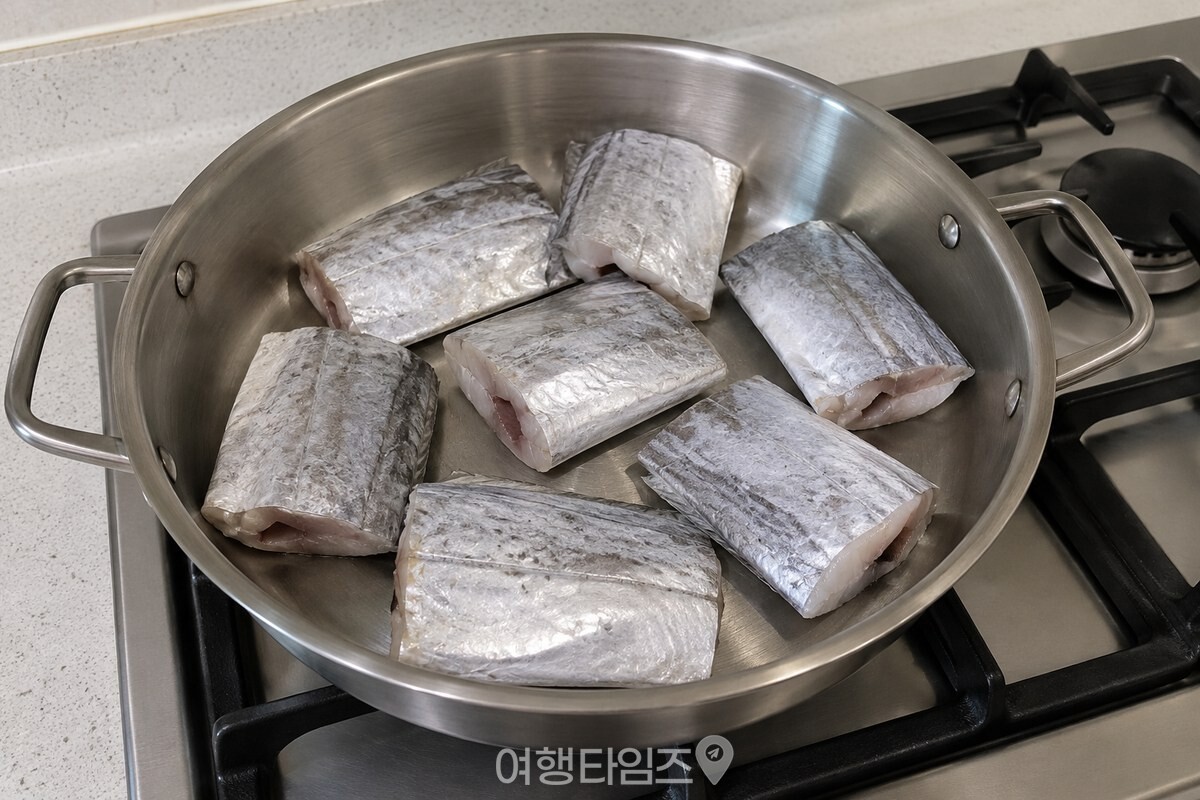 손질한 갈치 토막을 넓은 냄비 바닥에 겹치지 않게 펼쳐 담은 모습이다. / 기사 이해를 돕기 위한 생성형 이미지