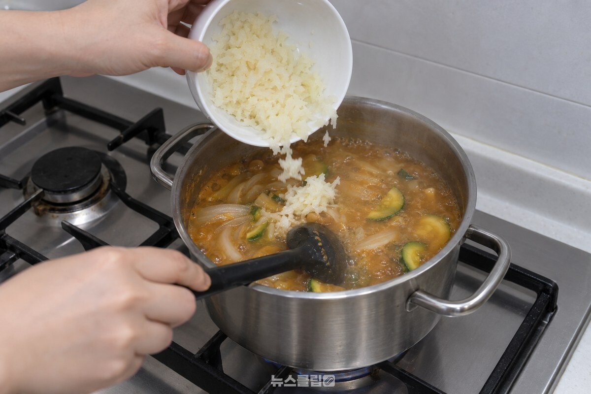 투명해진 양파가 든 찌개에 간 감자를 붓고 국자로 저어 주는 모습. / 기사 이해를 돕기 위한 생성형 이미지