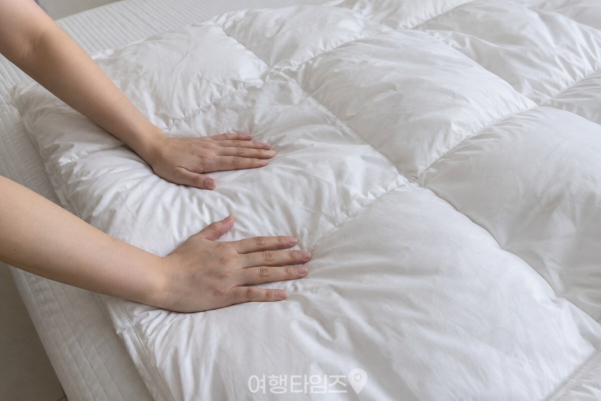 침대 위에 펼친 털이불의 얇은 부분을 손바닥 전체로 가볍게 누르고 있다. / 기사 이해를 돕기 위한 생성형 이미지