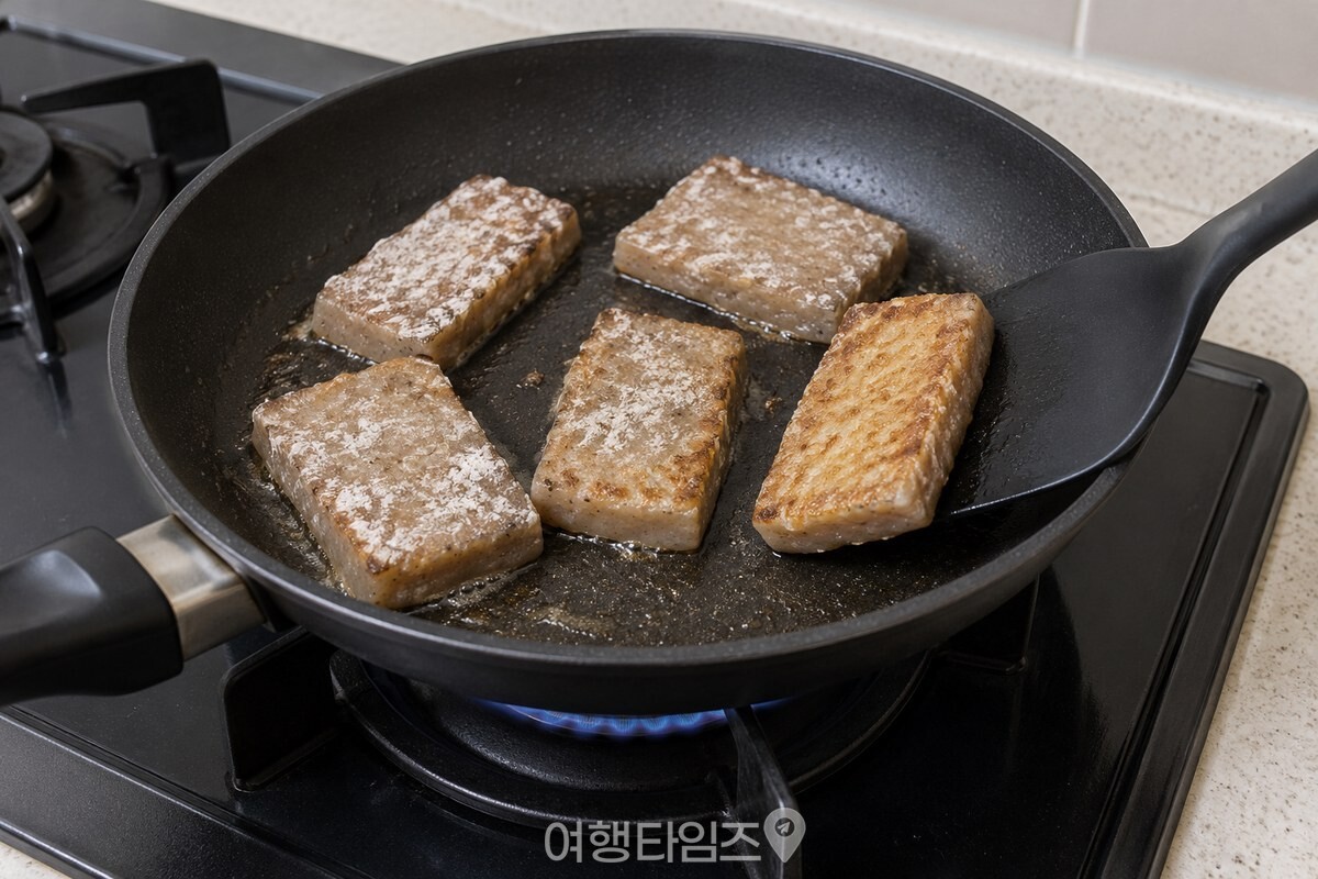 중불의 팬에서 간격을 두고 놓은 전분 입힌 도토리묵을 뒤집개로 뒤집는 모습. / 기사 이해를 돕기 위한 생성형 이미지