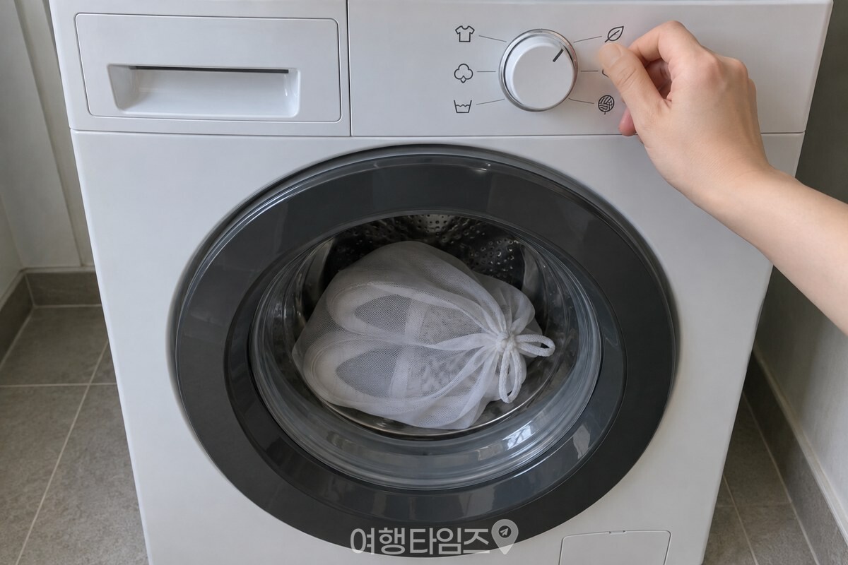 베개커버에 넣은 운동화를 앞문 드럼세탁기에 넣고 조작부를 약한 코스로 맞추는 손. / 기사 이해를 돕기 위한 생성형 이미지