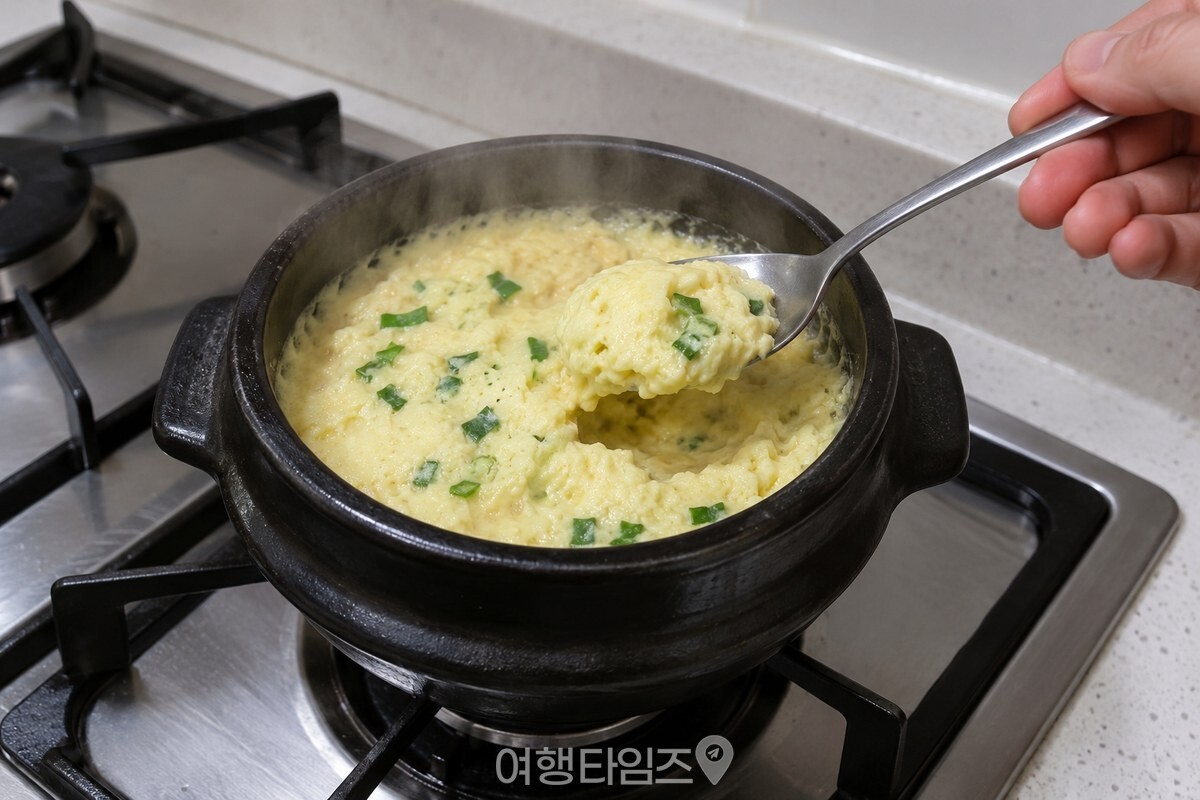 뚜껑을 연 뚝배기에서 김이 오르는 계란찜을 숟가락으로 떠보는 모습. / 기사 이해를 돕기 위한 생성형 이미지