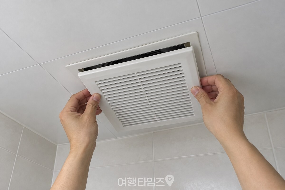 아래에서 올려다본 각도에서 한 사람의 두 손이 마른 흰 환풍기 덮개를 천장 환풍기 자리에 다시 맞춰 끼우는 모습. / 기사 이해를 돕기 위한 생성형 이미지