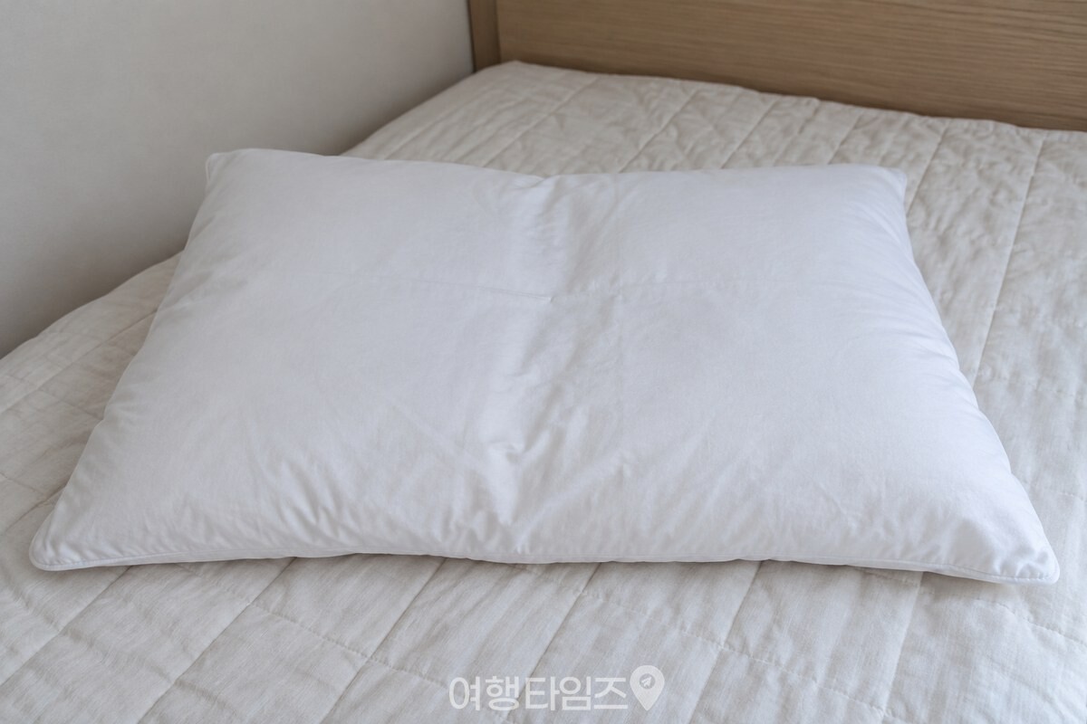 접었다가 손을 뗀 흰 베개 속통이 침대 위에서 다시 펴져 있는 모습이다. / 기사 이해를 돕기 위한 생성형 이미지