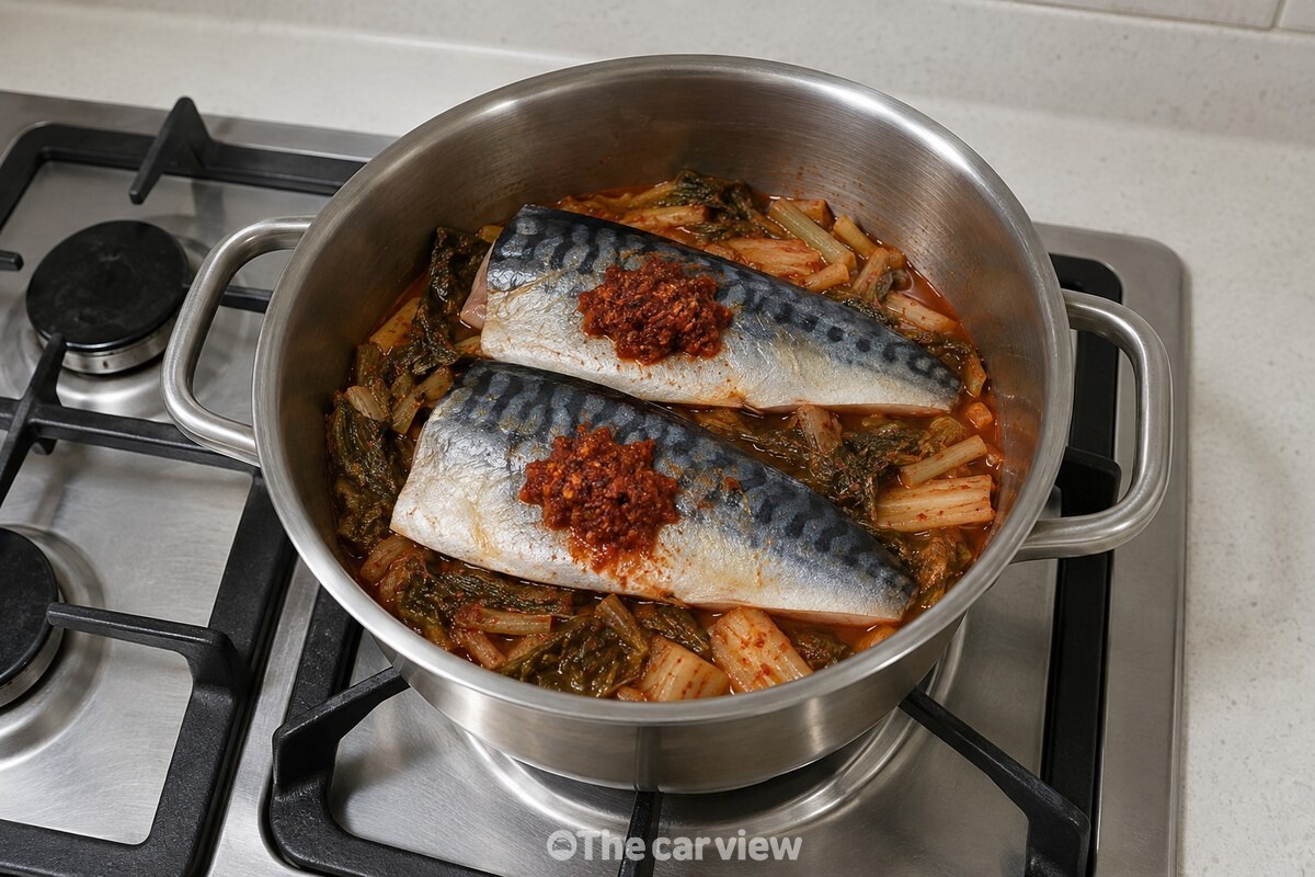 갓김치를 깐 냄비 위에 껍질 쪽을 올린 순살 고등어 두 쪽이 놓여 있다. / 기사 이해를 돕기 위한 생성형 이미지