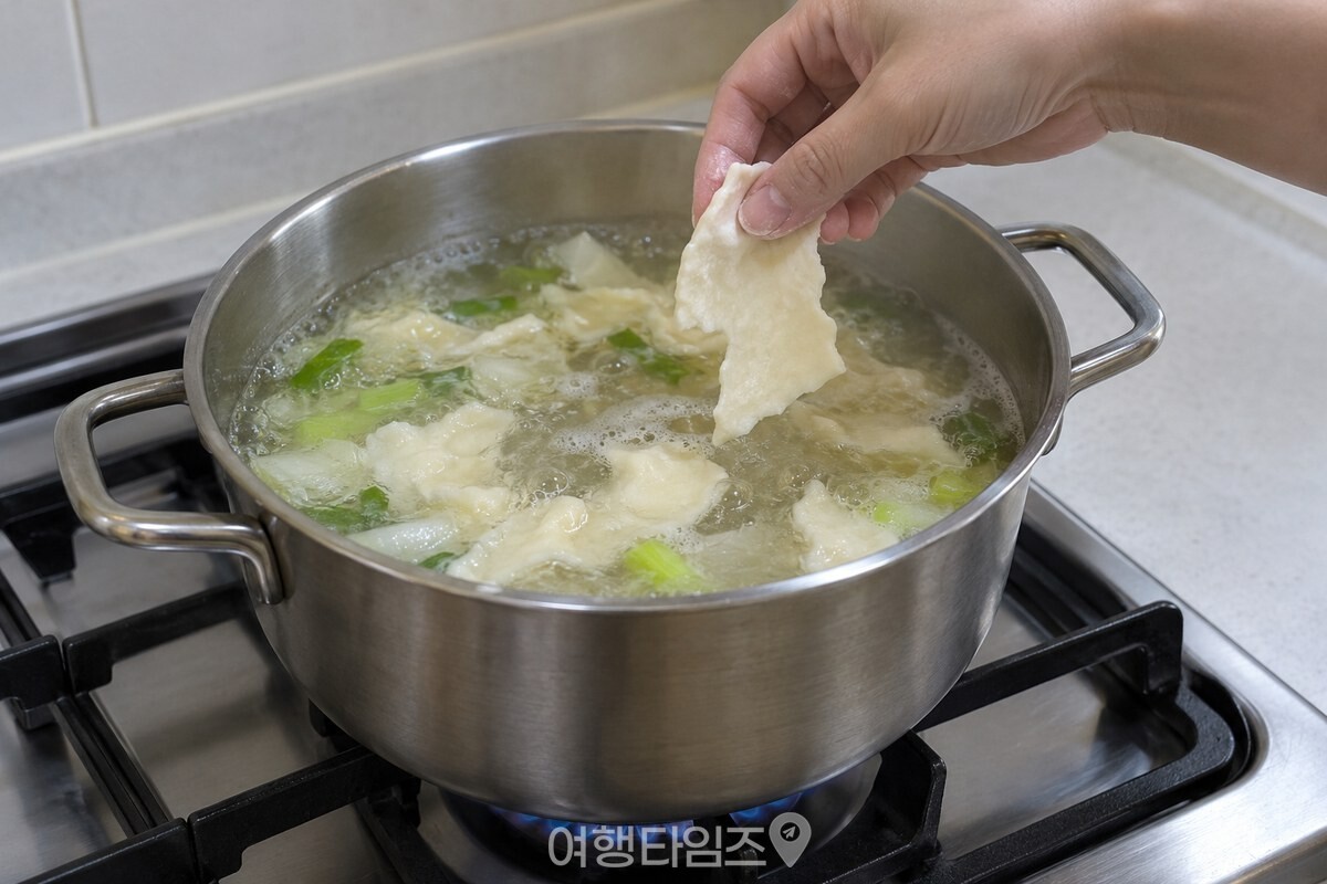 끓는 국물 위로 얇게 늘린 수제비 반죽 한 조각을 냄비에 넣고 있다. / 기사 이해를 돕기 위한 생성형 이미지
