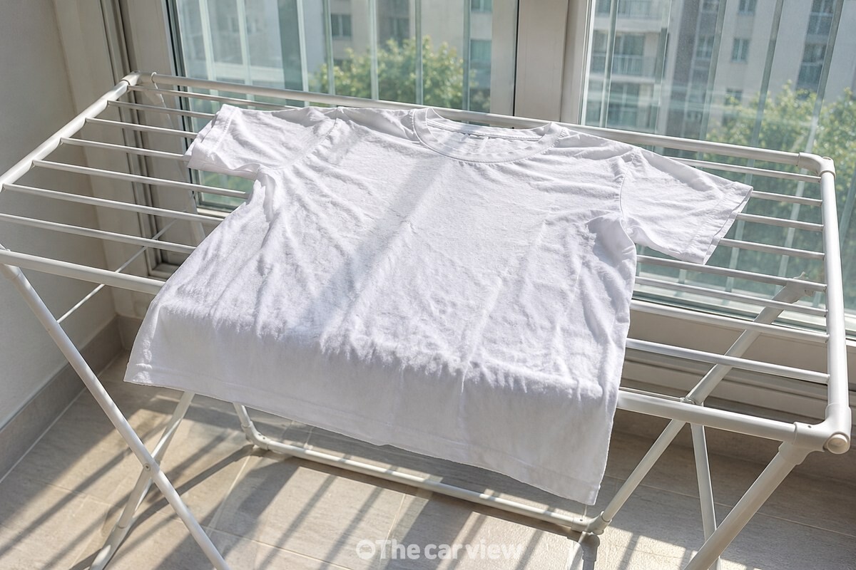 촉촉한 흰 면 티셔츠를 베란다 건조대 위에 앞면이 보이도록 평평하게 펼쳐 둔 모습. / 기사 이해를 돕기 위한 생성형 이미지