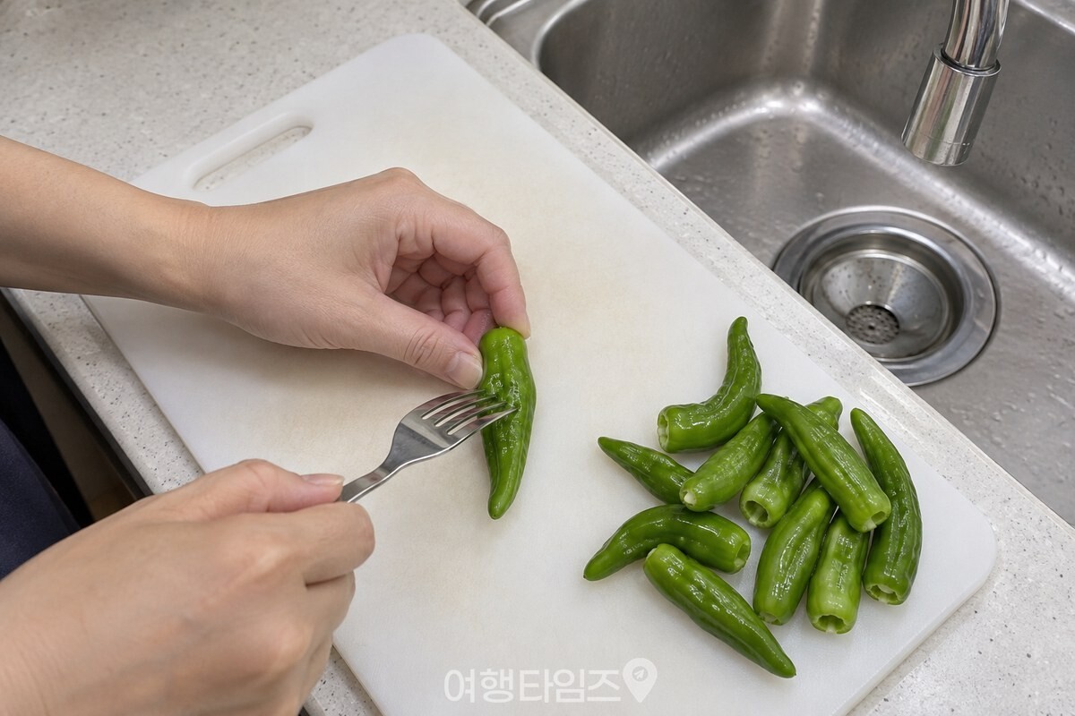 깨끗이 씻어 꼭지를 정리한 꽈리고추에 포크로 작은 구멍을 내고 있다. / 기사 이해를 돕기 위한 생성형 이미지