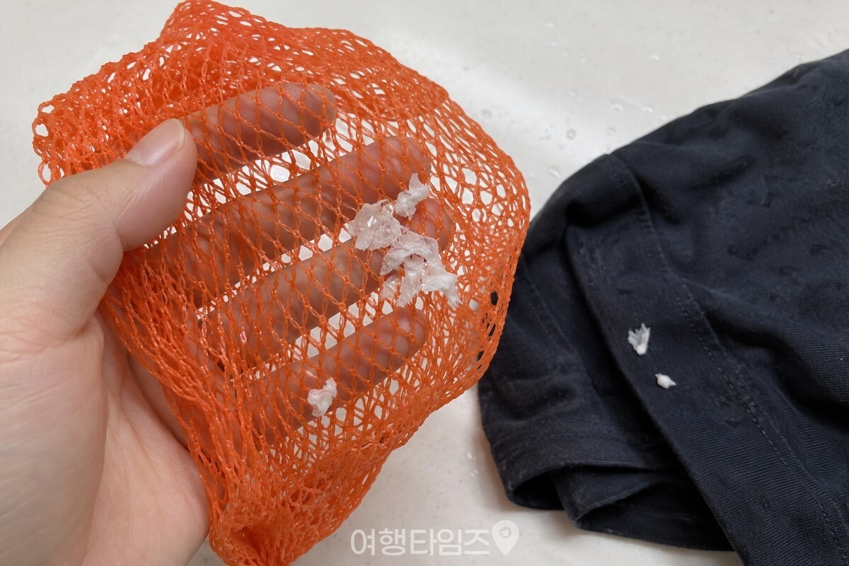 양파망의 그물코 사이에 젖은 옷감에서 나온 휴지 조각이 모여 있다. / 기사 이해를 돕기 위한 생성형 이미지