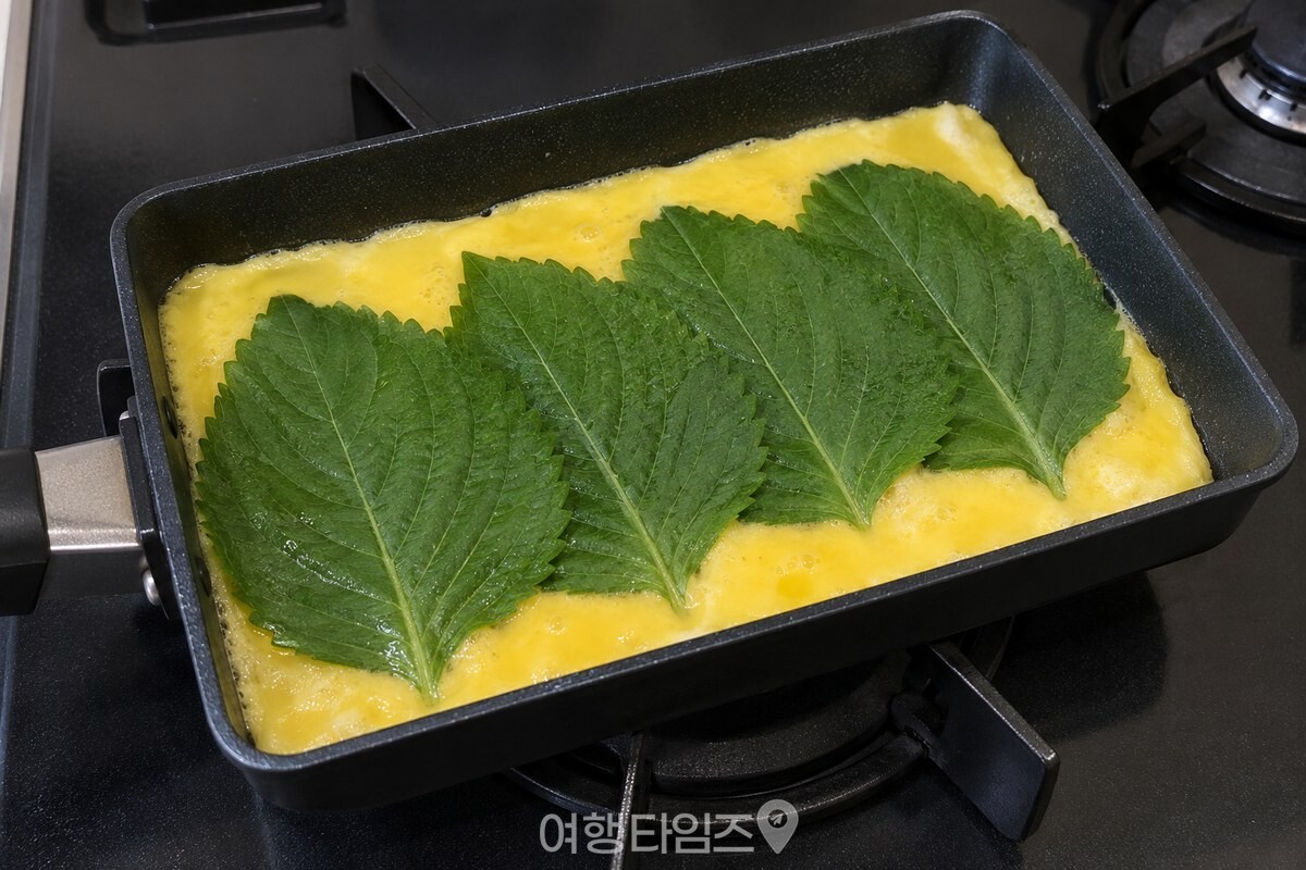 달걀 위에 잎째 올린 깻잎이 말기 전 넓게 펼쳐져 있다. / 기사 이해를 돕기 위한 생성형 이미지