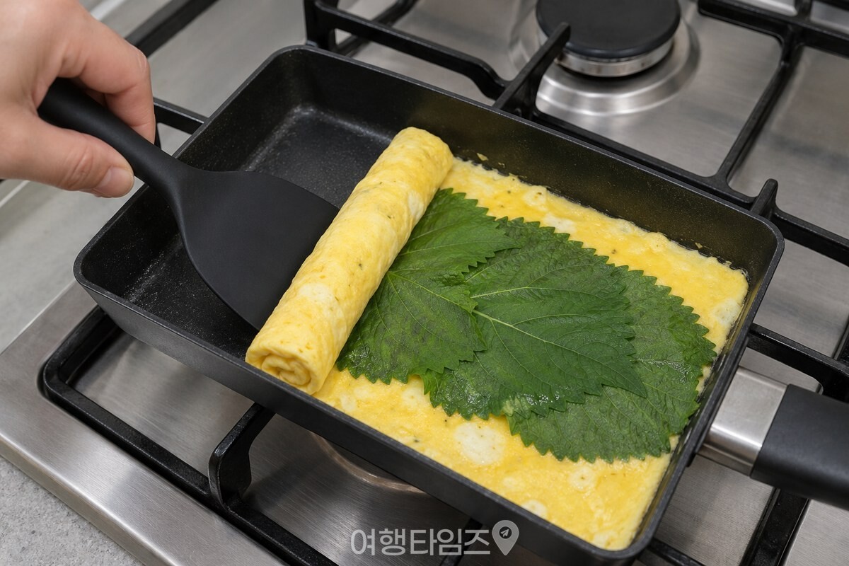 깻잎을 깐 달걀을 뒤집개로 한쪽부터 말아 가는 모습이다. / 기사 이해를 돕기 위한 생성형 이미지