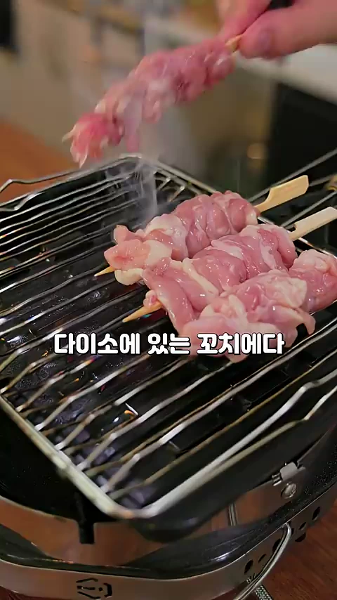 나무 꼬치에 꿴 생닭고기를 석쇠 위에서 굽고 있는 모습
