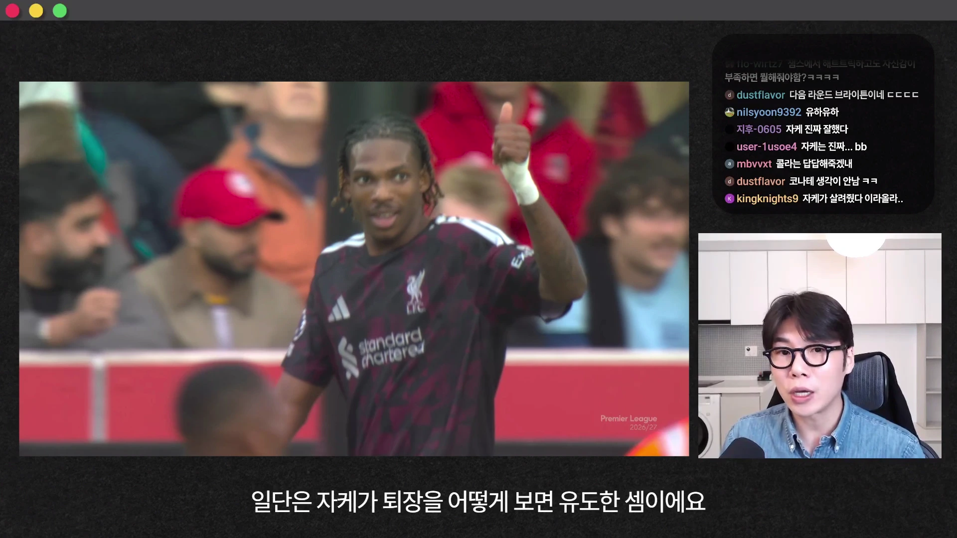 축구 경기장에서 엄지손가락을 치켜세우고 있는 리버풀 유니폼을 입은 선수와 화면 오른쪽 아래에 카메라를 응시하며 말하는 남성의 모습이 담긴 영상 캡처 화면입니다.