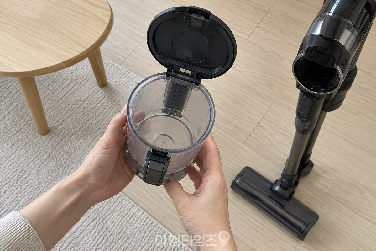 작은 탁자를 옮긴 뒤 비워 둔 먼지통을 확인하는 거실 청소 준비 모습. / 기사 이해를 돕기 위한 생성형 이미지