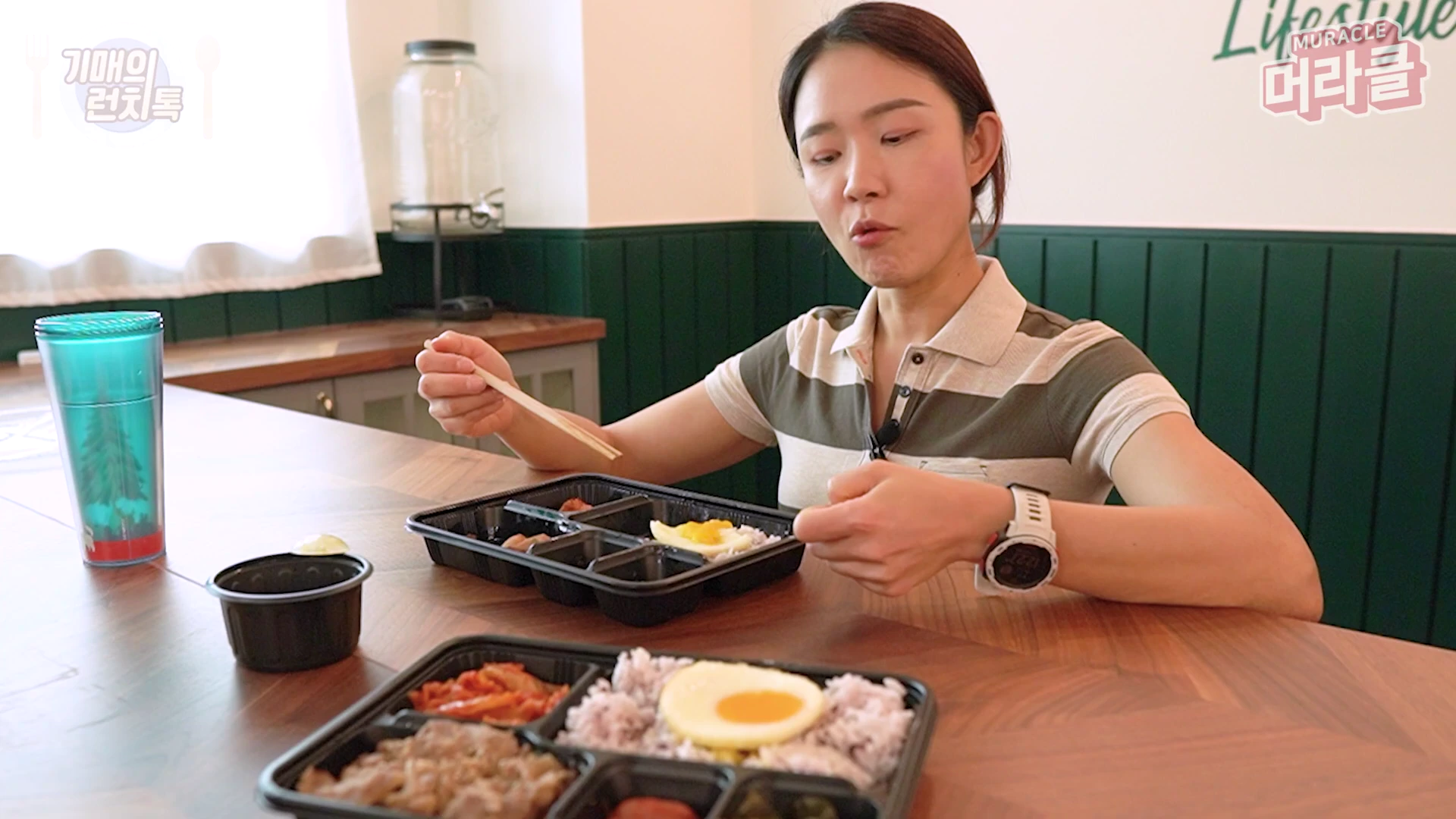 한 여성이 테이블에 앉아 도시락을 먹으며 이야기를 나누고 있는 모습입니다.