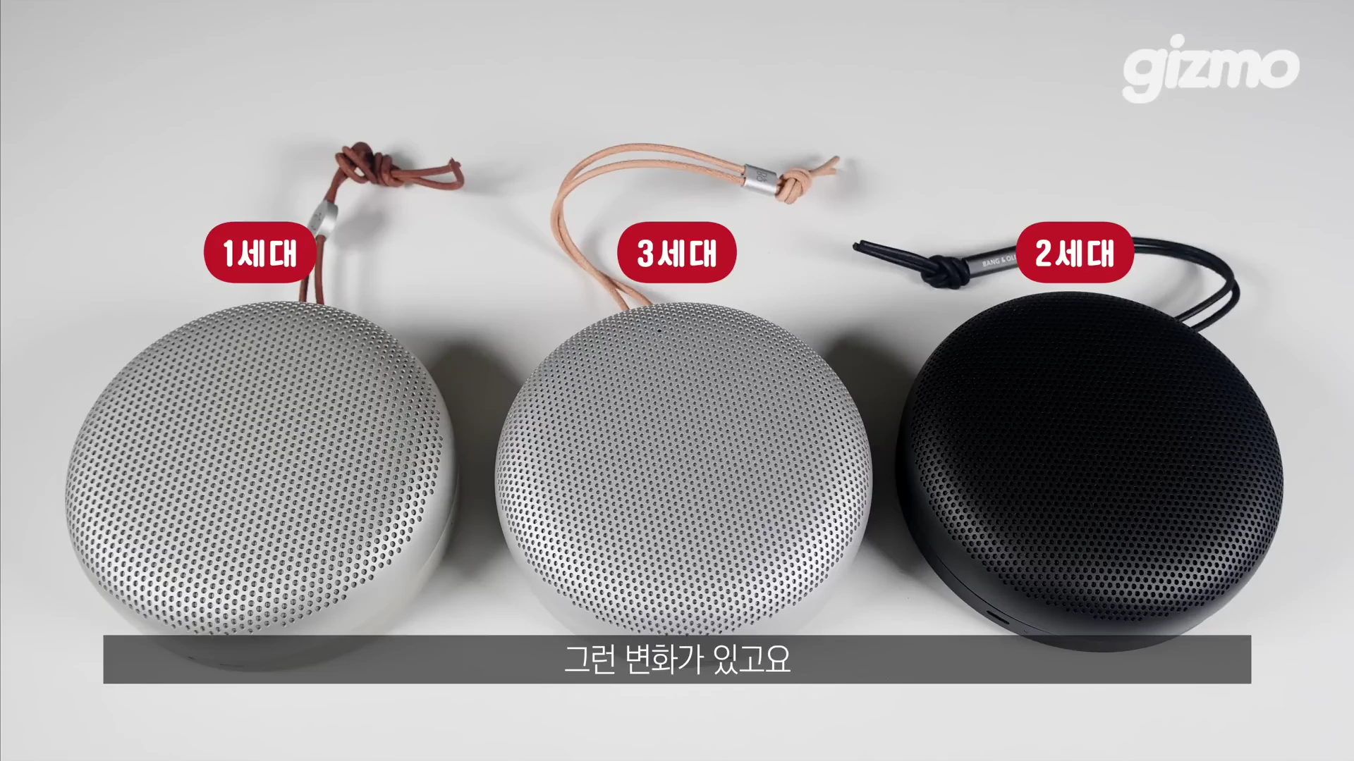 흰색 배경 위에 1세대, 3세대, 2세대 뱅앤올룹슨 베오사운드 A1 스피커가 나란히 놓여 있으며, 각 스피커 위에는 세대 번호가 적힌 빨간색 표지가 떠 있다.