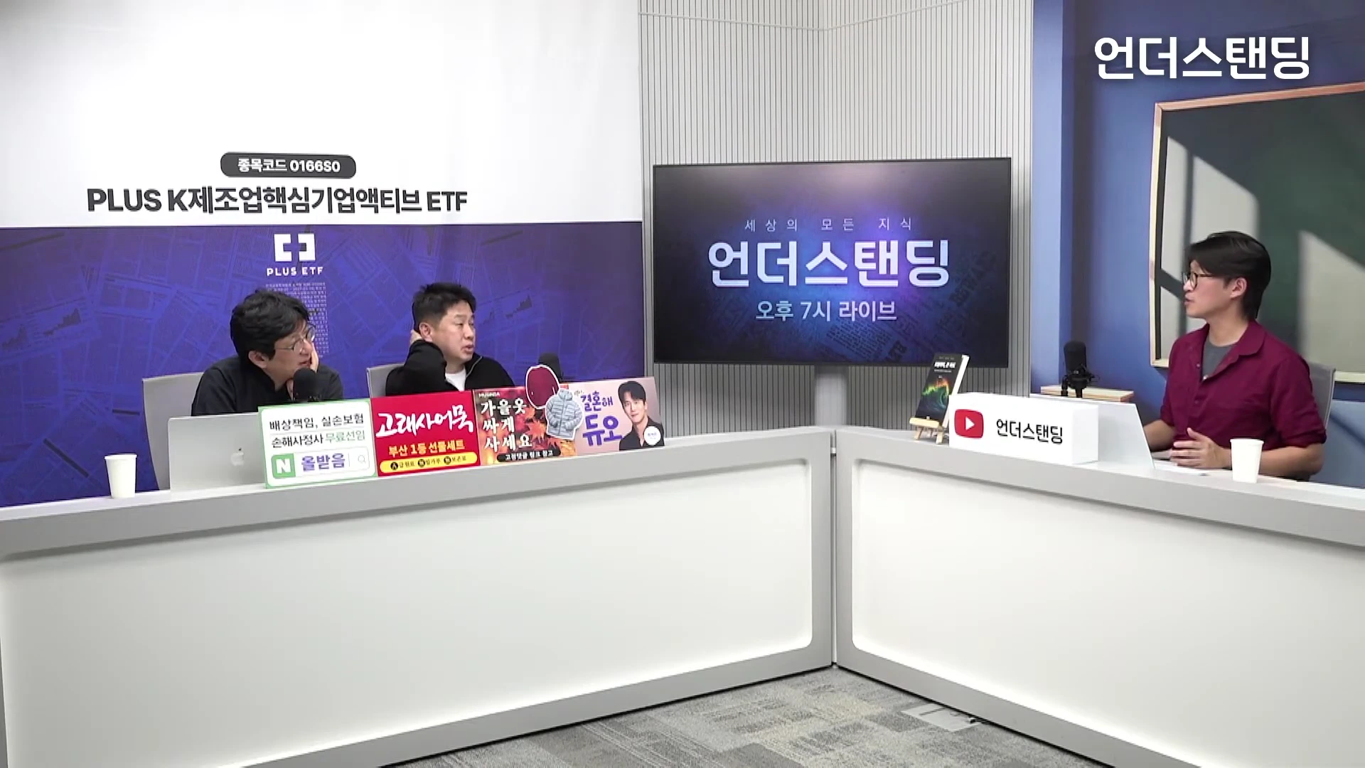 세 명의 남성이 흰색 테이블을 사이에 두고 앉아 대화를 나누고 있는 스튜디오 세트의 모습입니다.