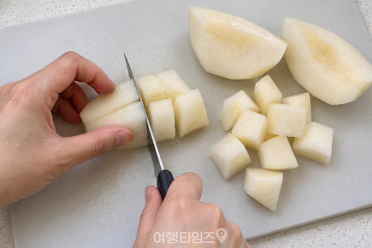 껍질과 씨 부분을 제거한 배를 1~1.5cm 크기로 깍둑썰고 있는 모습. / 기사 이해를 돕기 위한 생성형 이미지
