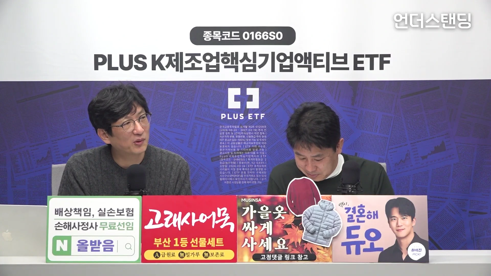두 남자가 스튜디오에서 마이크를 앞에 두고 대화를 나누고 있으며, 화면 하단에는 다양한 광고 문구가 적힌 패널들이 배치되어 있습니다.