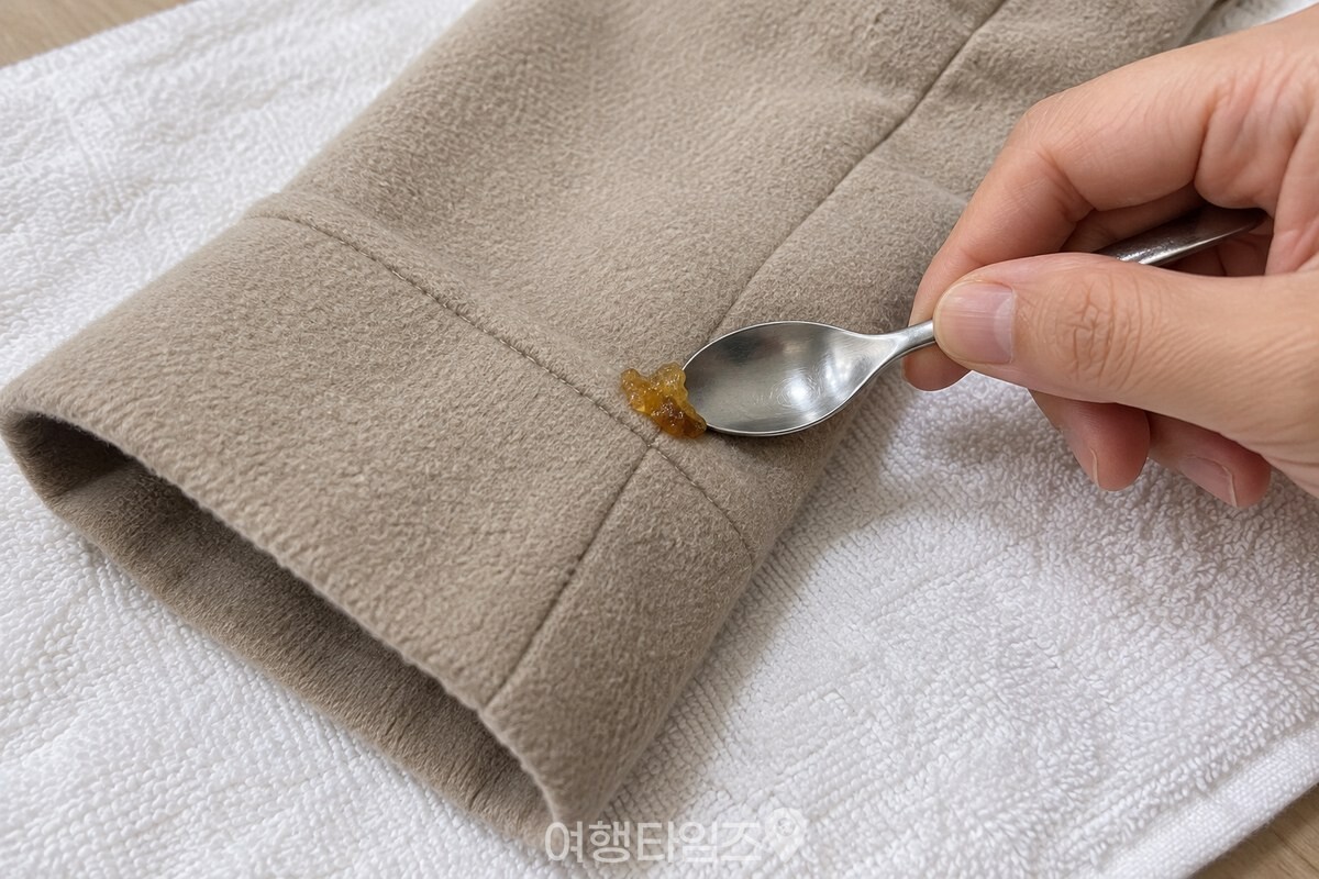 숟가락 끝으로 외투 표면의 송진 덩어리를 조심스럽게 들어 올리는 모습. / 기사 이해를 돕기 위한 생성형 이미지