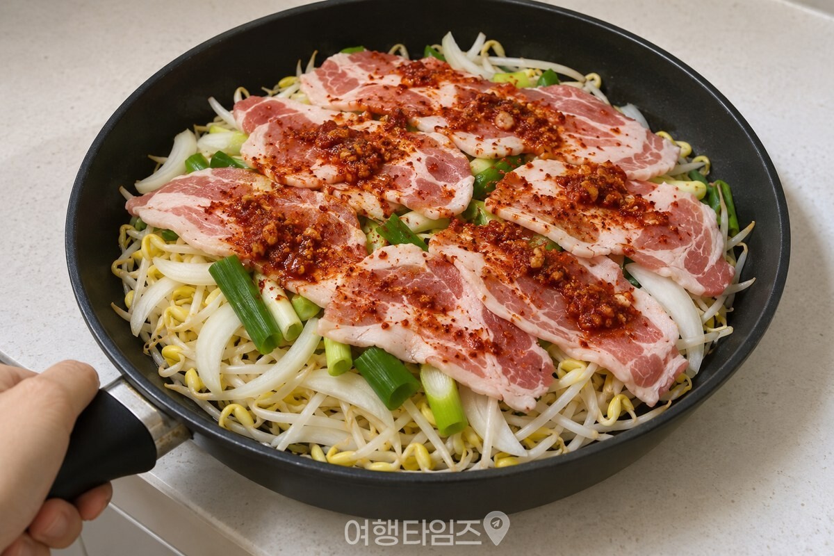 넓은 팬 바닥에 콩나물을 깔고 그 위에 고기와 채소를 차례로 올린 모습. / 기사 이해를 돕기 위한 생성형 이미지
