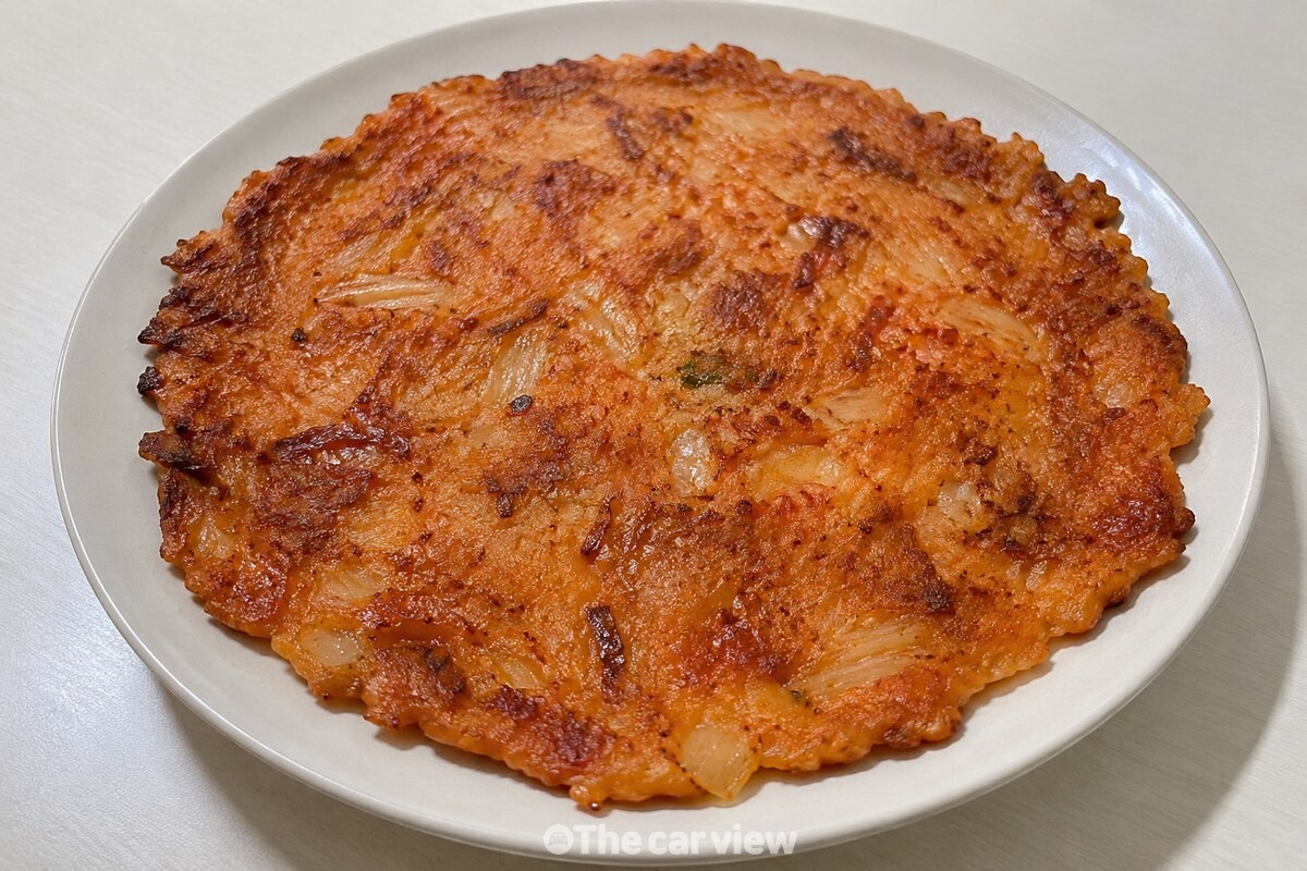 접시에 담긴 김치전이 노릇한 가장자리와 김치 조각을 드러낸 채 놓여 있는 모습 / 기사 이해를 돕기 위한 생성형 이미지