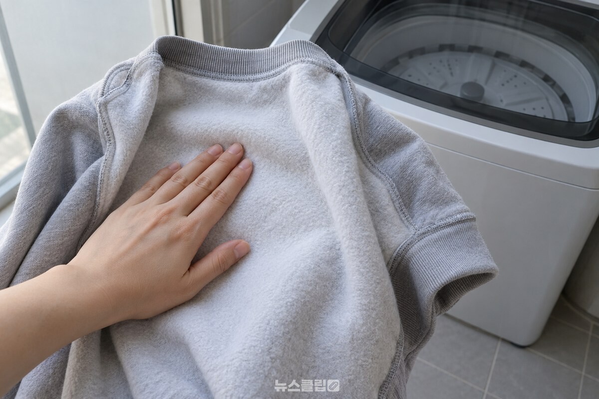 세탁을 마친 뒤집은 기모 티셔츠 안쪽을 손바닥으로 부드럽게 쓸어 보는 모습 / 기사 이해를 돕기 위한 생성형 이미지