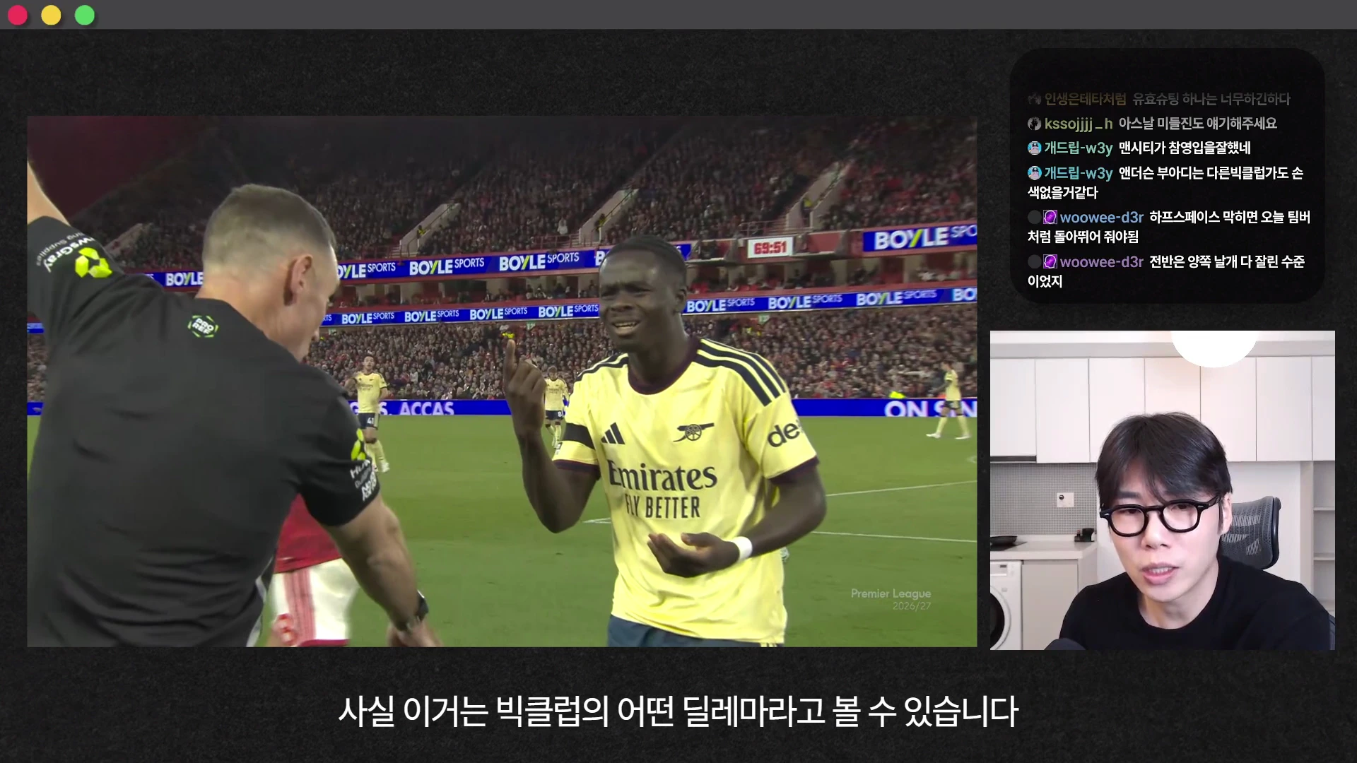 축구 경기 중 심판에게 항의하는 노란색 유니폼의 선수와 그 옆에서 이를 지켜보는 심판, 그리고 화면 오른쪽 하단에는 안경을 쓴 남성이 출연 중인 방송 화면