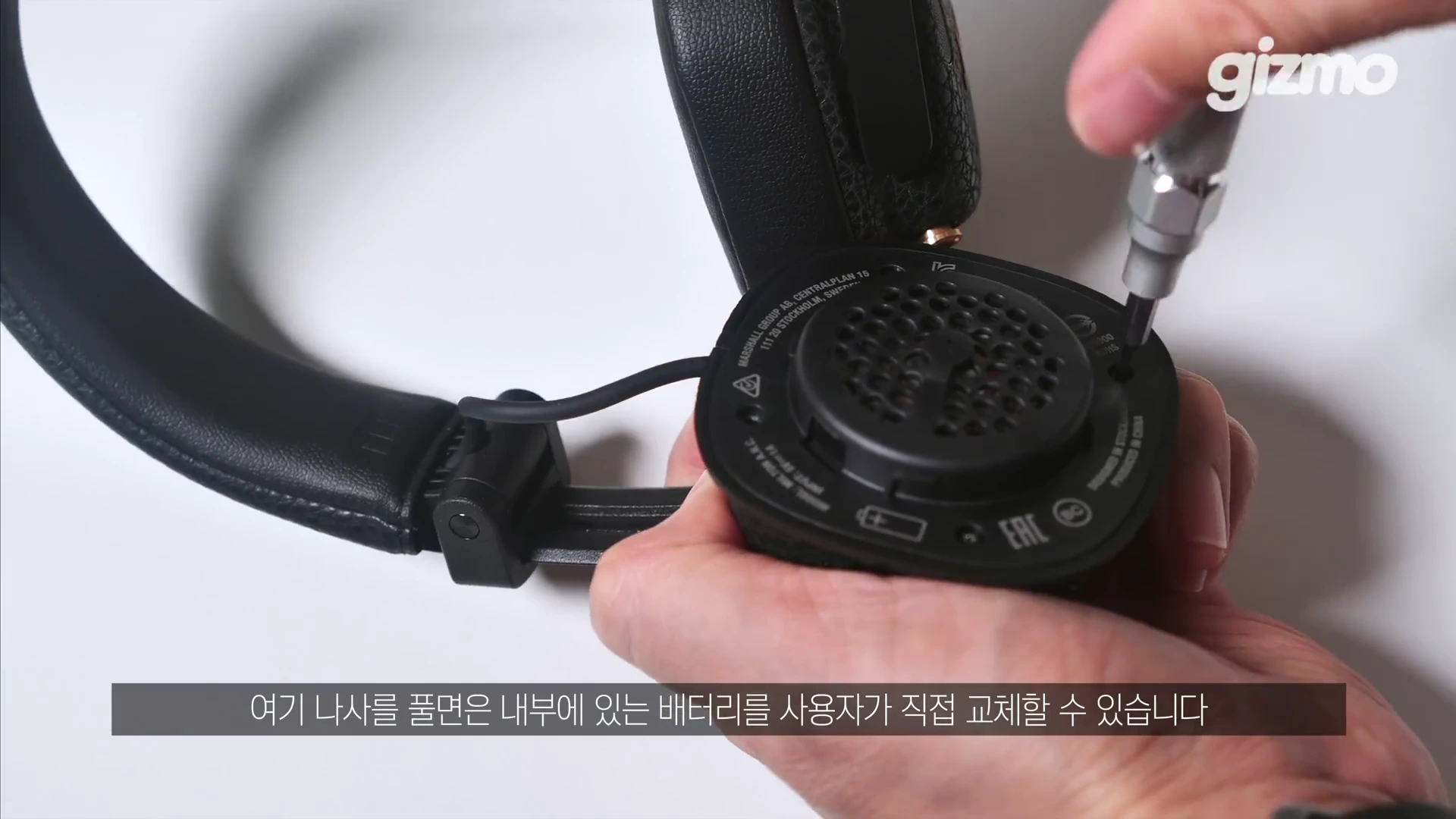 헤드폰의 이어패드를 분리하고 드라이버 유닛 부분의 나사를 드라이버로 풀고 있는 손.