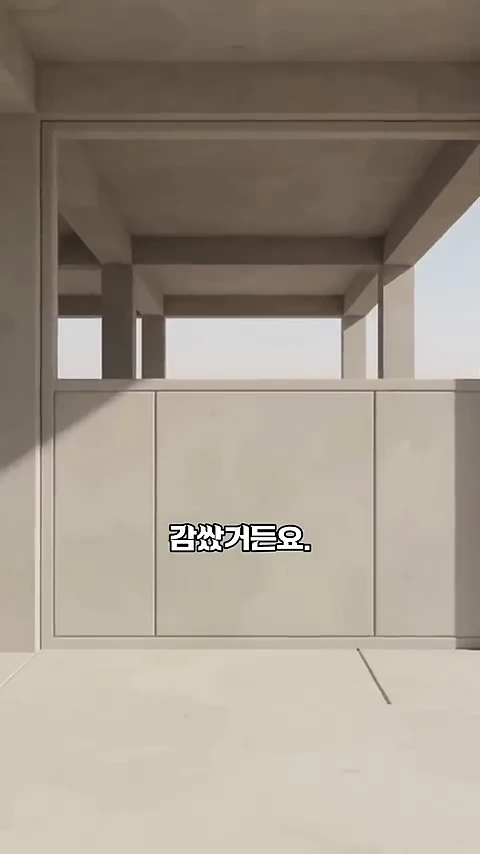 건물의 1층 기둥 사이가 매끄러운 벽면으로 막혀 있는 모습이며, 화면 중앙에는 '감쌌거든요.'라는 자막이 표시되어 있습니다.
