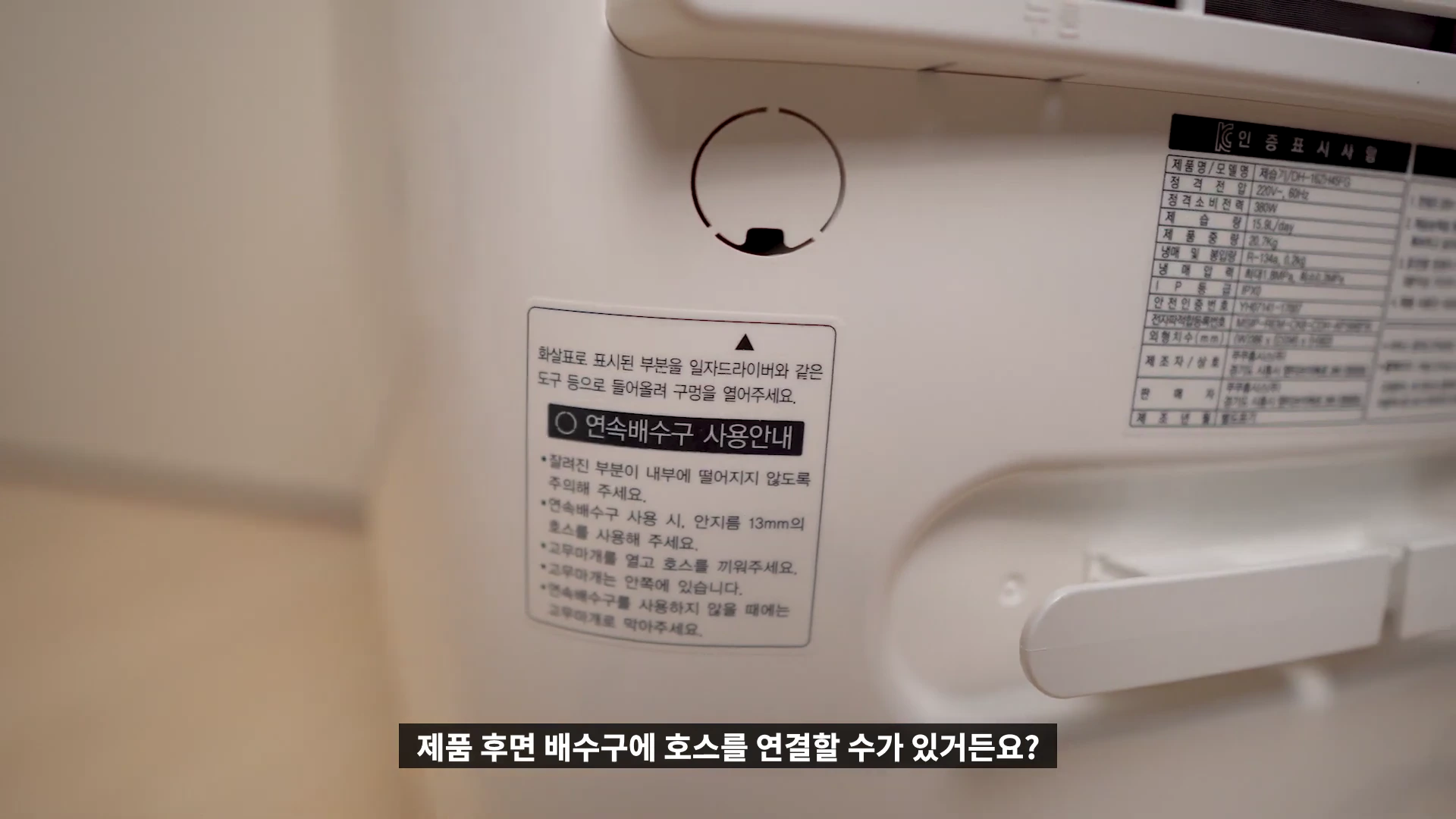 제습기 뒷면에 부착된 연속 배수구 사용 안내 스티커와 제품 사양 정보가 적힌 라벨이 붙어 있는 모습