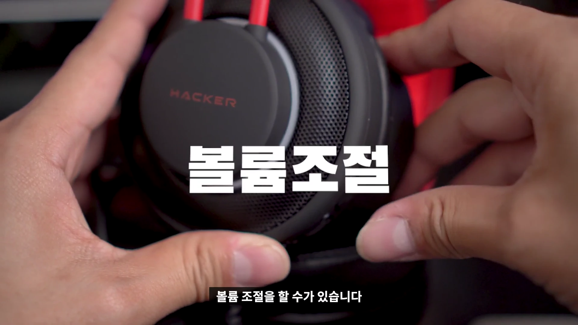 두 손으로 검은색 게이밍 헤드셋의 측면부를 잡고 있는 모습이며 화면 중앙에 볼륨조절이라는 흰색 큰 글씨가 강조되어 있습니다.