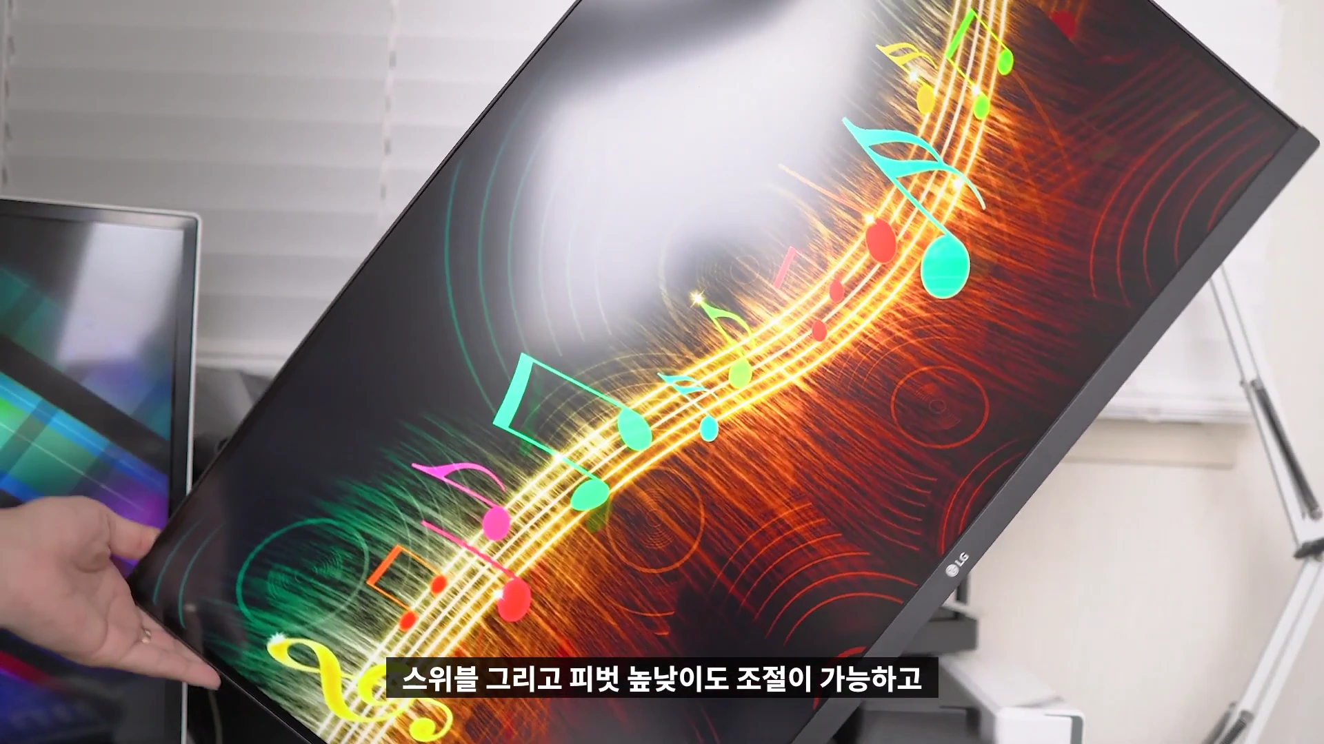 사람의 손이 모니터 화면을 대각선으로 기울여 회전시키고 있는 모습.