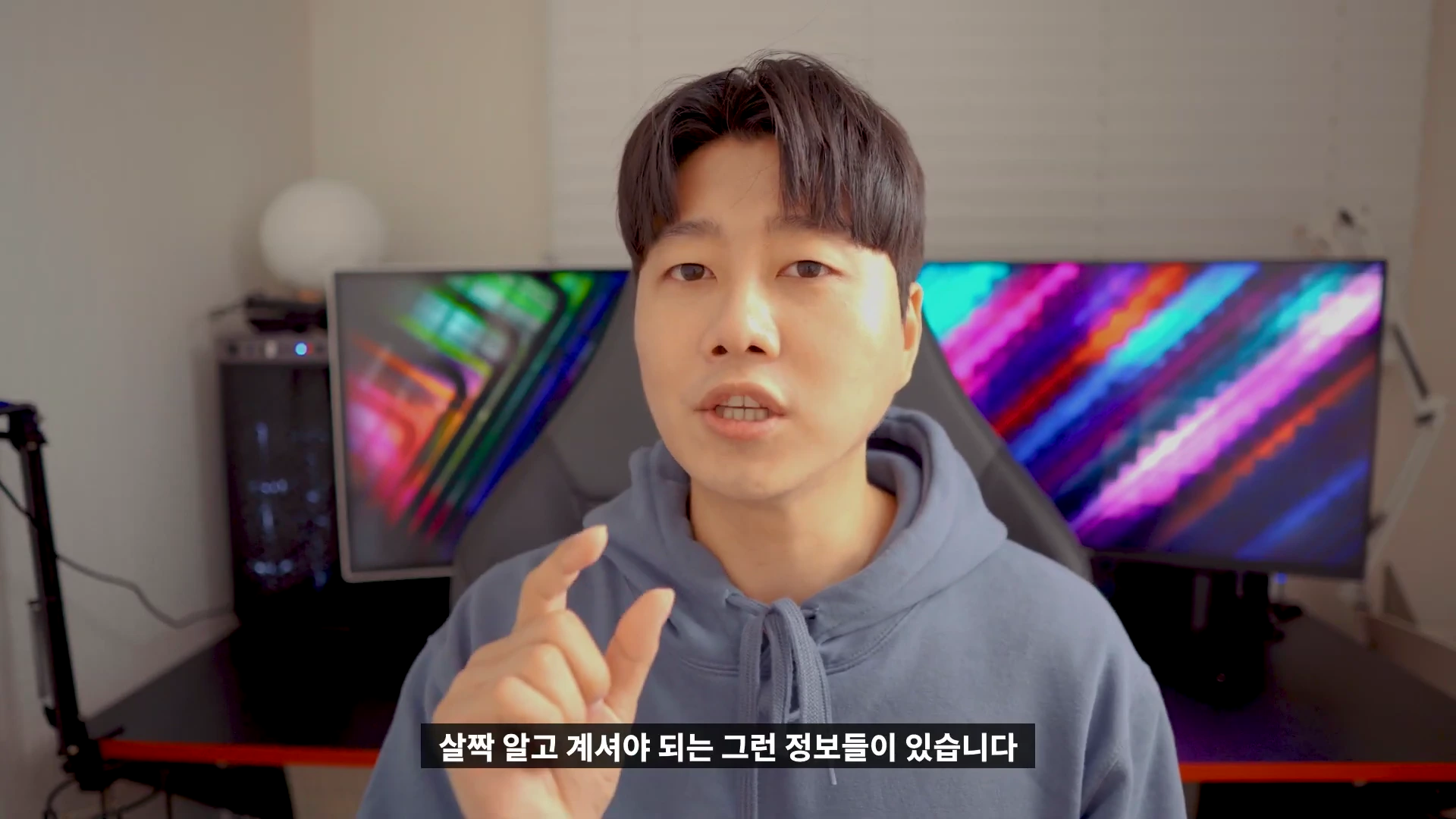 푸른색 후드티를 입은 남성이 카메라를 보며 손가락으로 작은 크기를 표시하고 있는 영상 화면