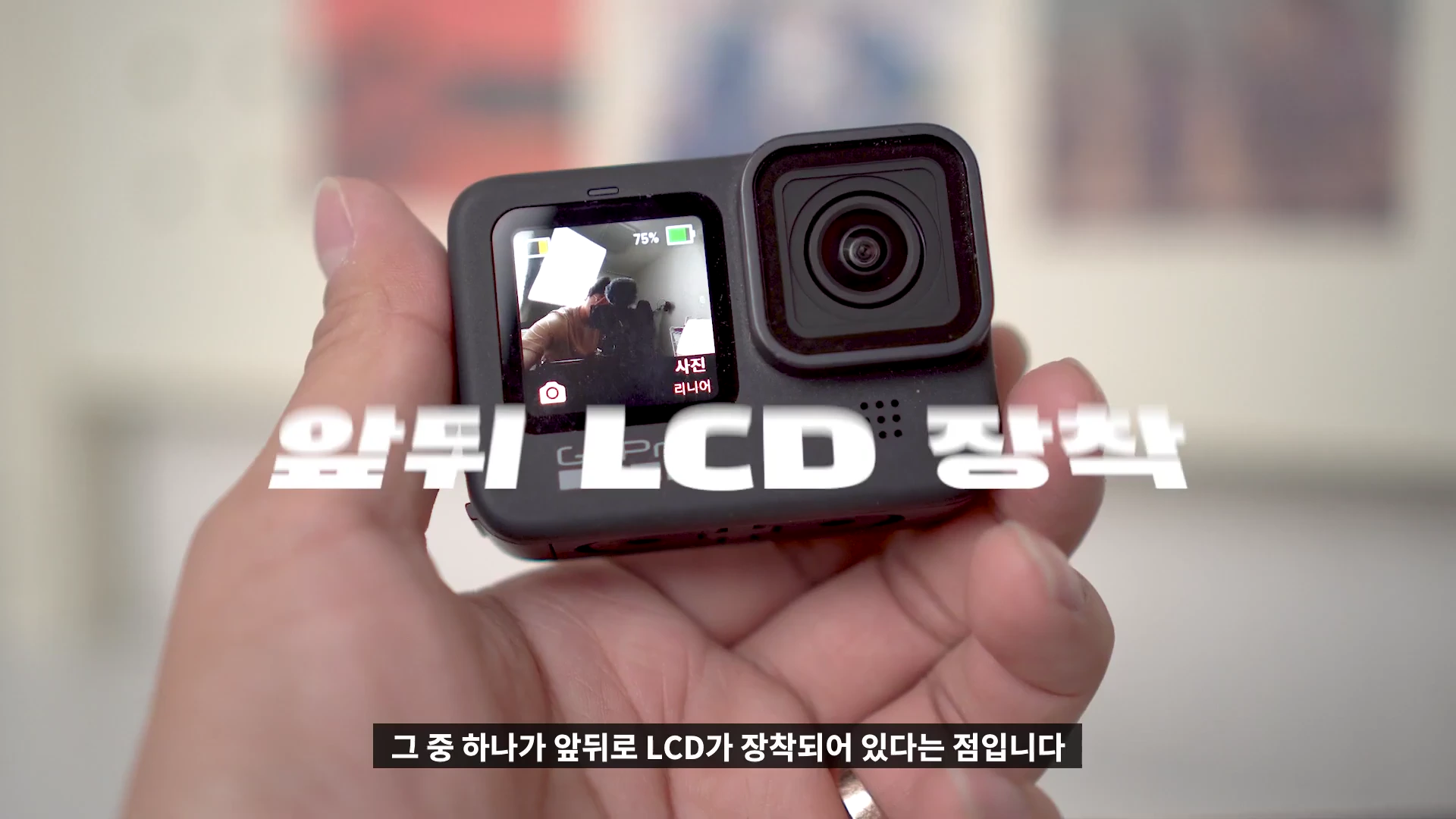 사람의 손에 들린 검은색 액션캠의 전면 모습이며, 전면 LCD 화면에는 촬영 구도가 표시되고 '앞뒤 LCD 장착'이라는 흰색 자막이 크게 적혀 있습니다.