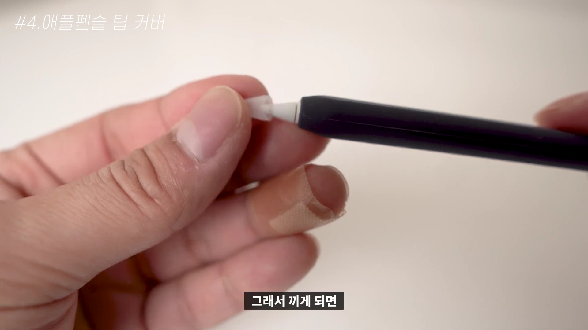 손으로 애플펜슬 끝에 투명한 실리콘 재질의 팁 커버를 끼우는 모습
