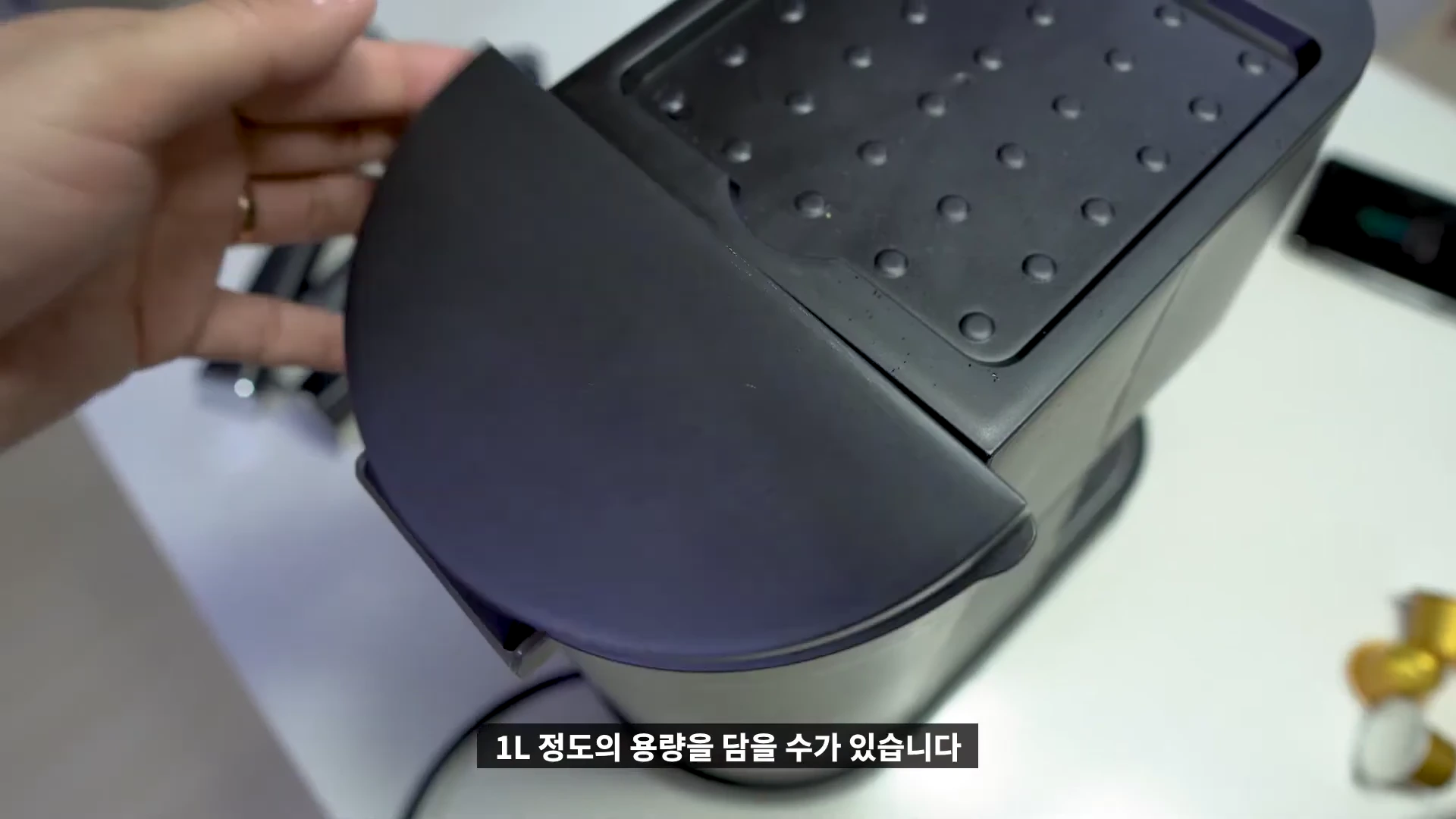 커피머신 상단의 컵 워머 판과 물탱크 덮개가 열려 있는 모습이며, 사용자의 손이 기기를 조작하고 있다.