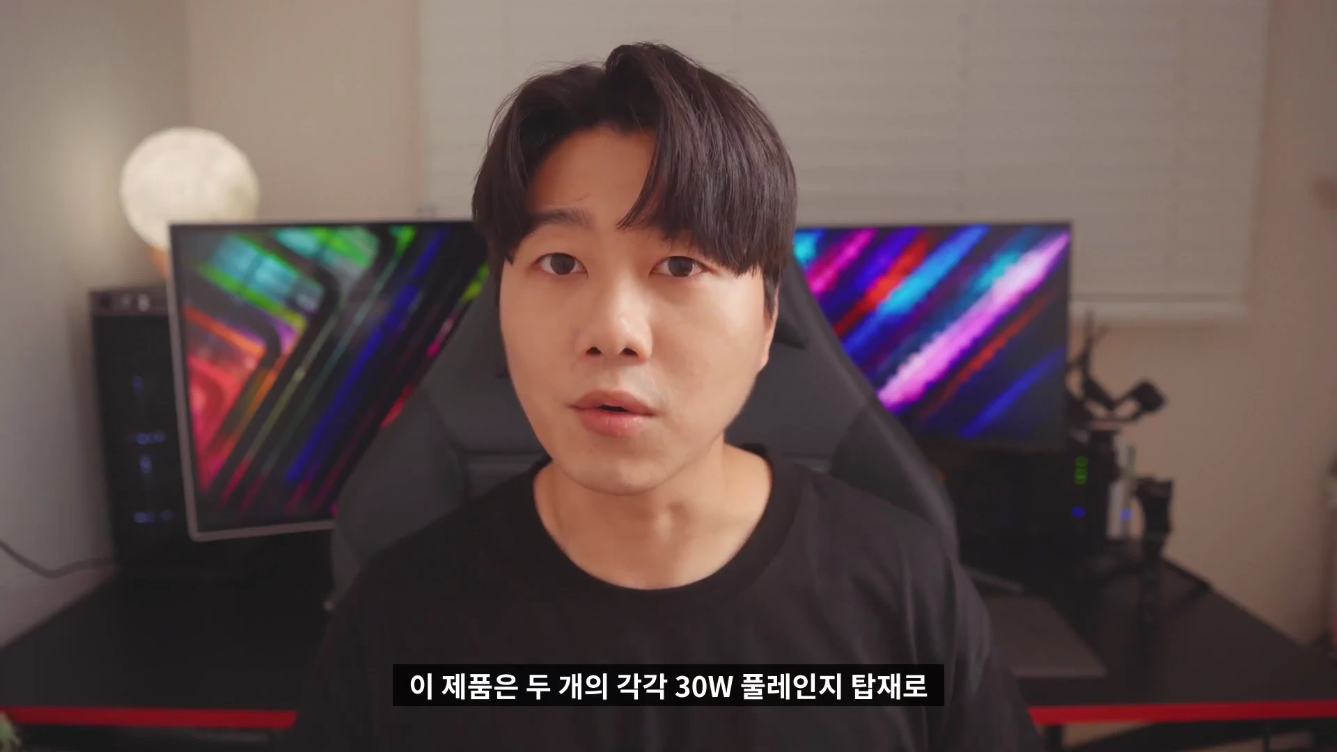 검은색 티셔츠를 입은 남성이 방 안에서 정면을 응시하며 이야기하고 있고, 하단에는 한국어 자막이 표시되어 있습니다.