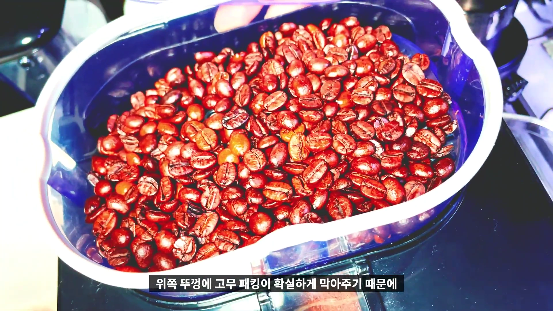 커피 그라인더 상단 투명 호퍼 안에 갈색으로 로스팅 된 커피 원두가 가득 차 있는 모습
