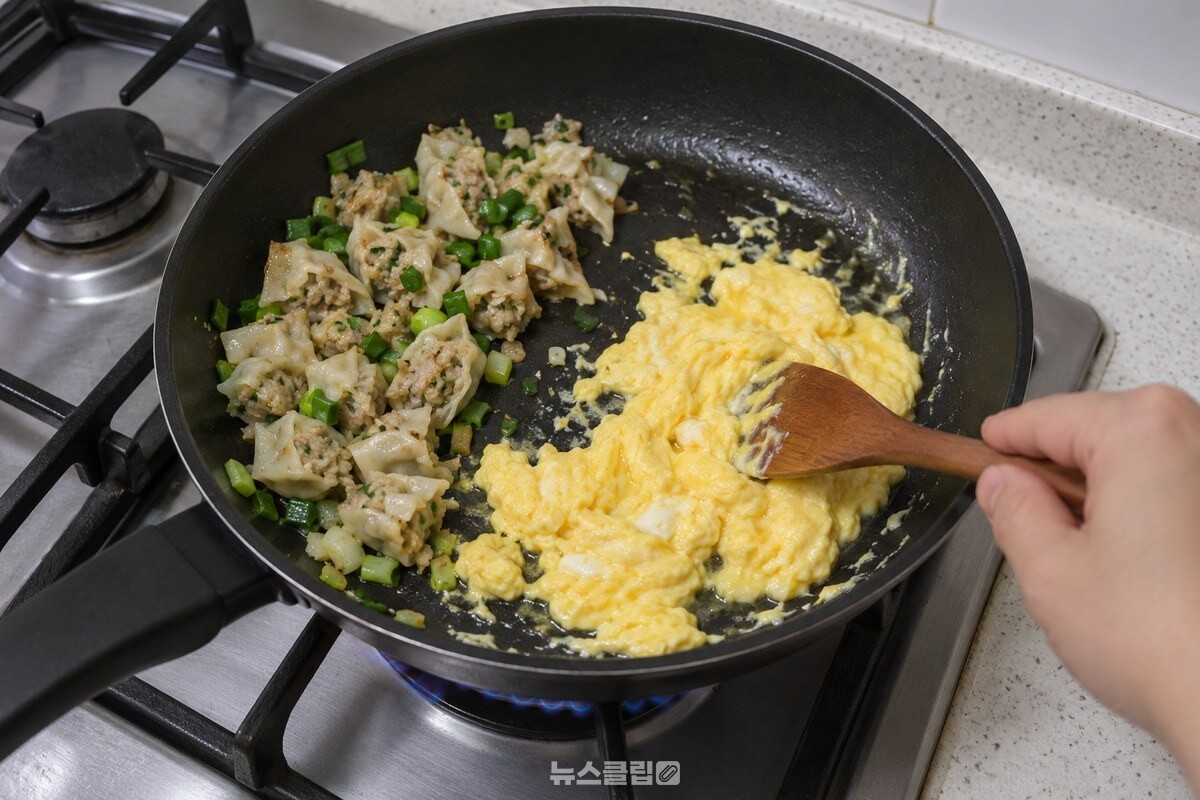 팬 한쪽의 만두와 파 옆에서 달걀을 촉촉하게 볶는 단계. / 기사 이해를 돕기 위한 생성형 이미지